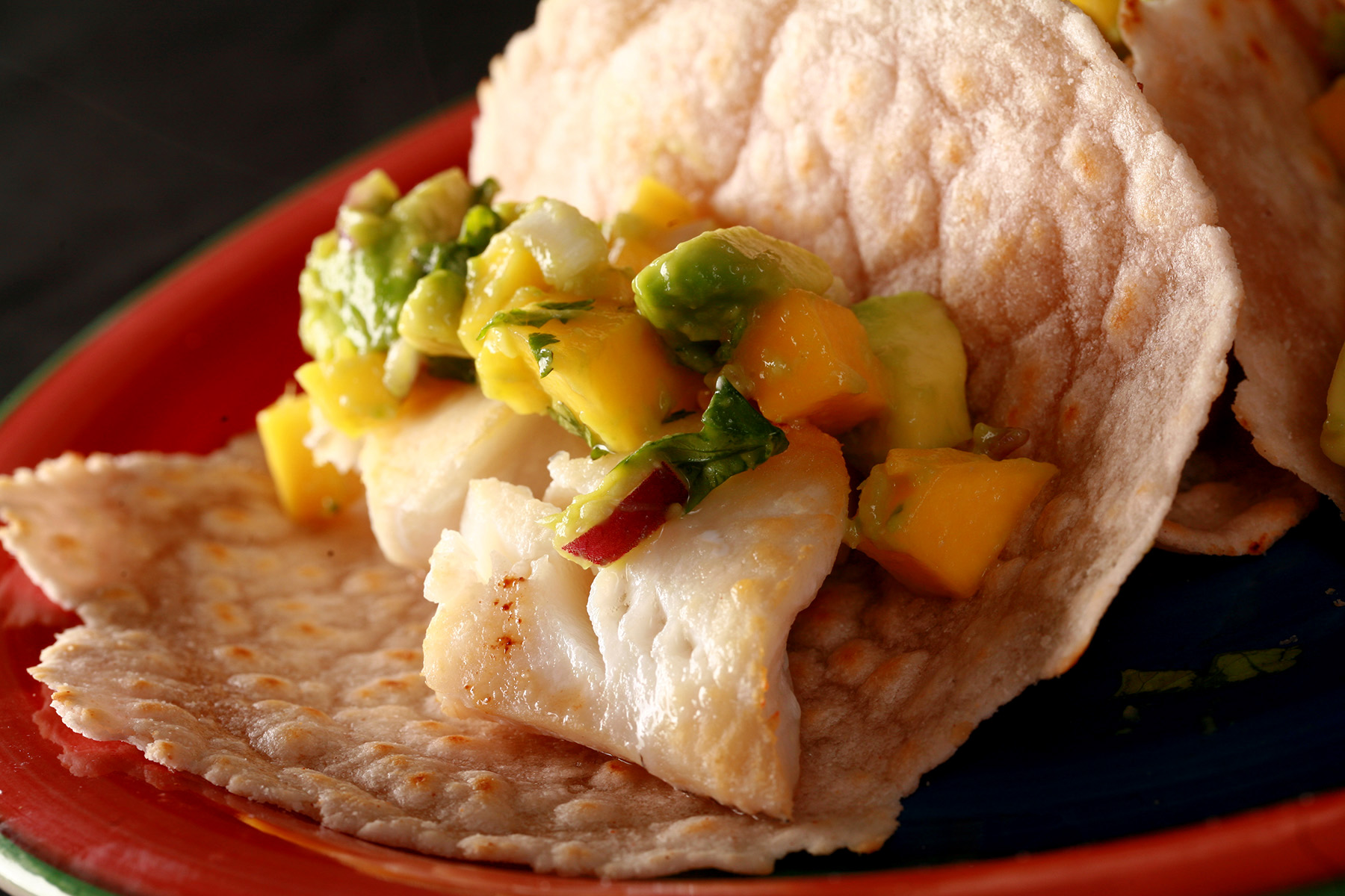 Cassava flour paleo fish tacos, with mango salsa, on a red plate.