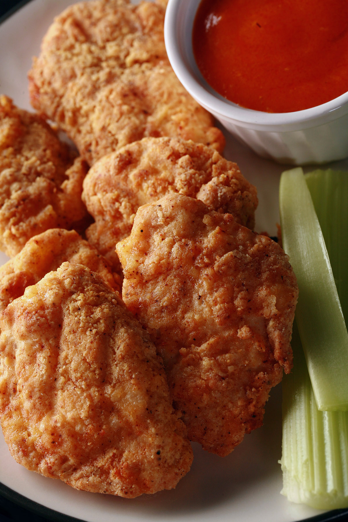 A plate of air fryer gluten free chicken nuggets, celery, and dip.