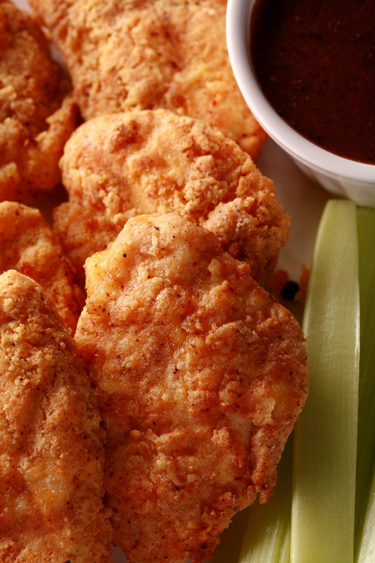 A plate of air fried gluten-free chicken nuggets, celery, and dip.