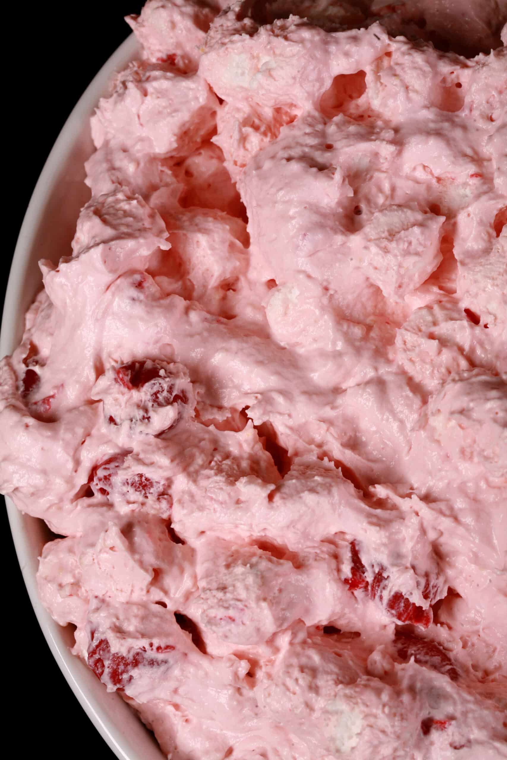 A serving bowl of bright pink cherry cheesecake fluff salad.
