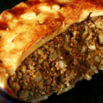 A close up photo of a cut-open chicken mushroom tourtiere pie. The crust has maple leaves on it.