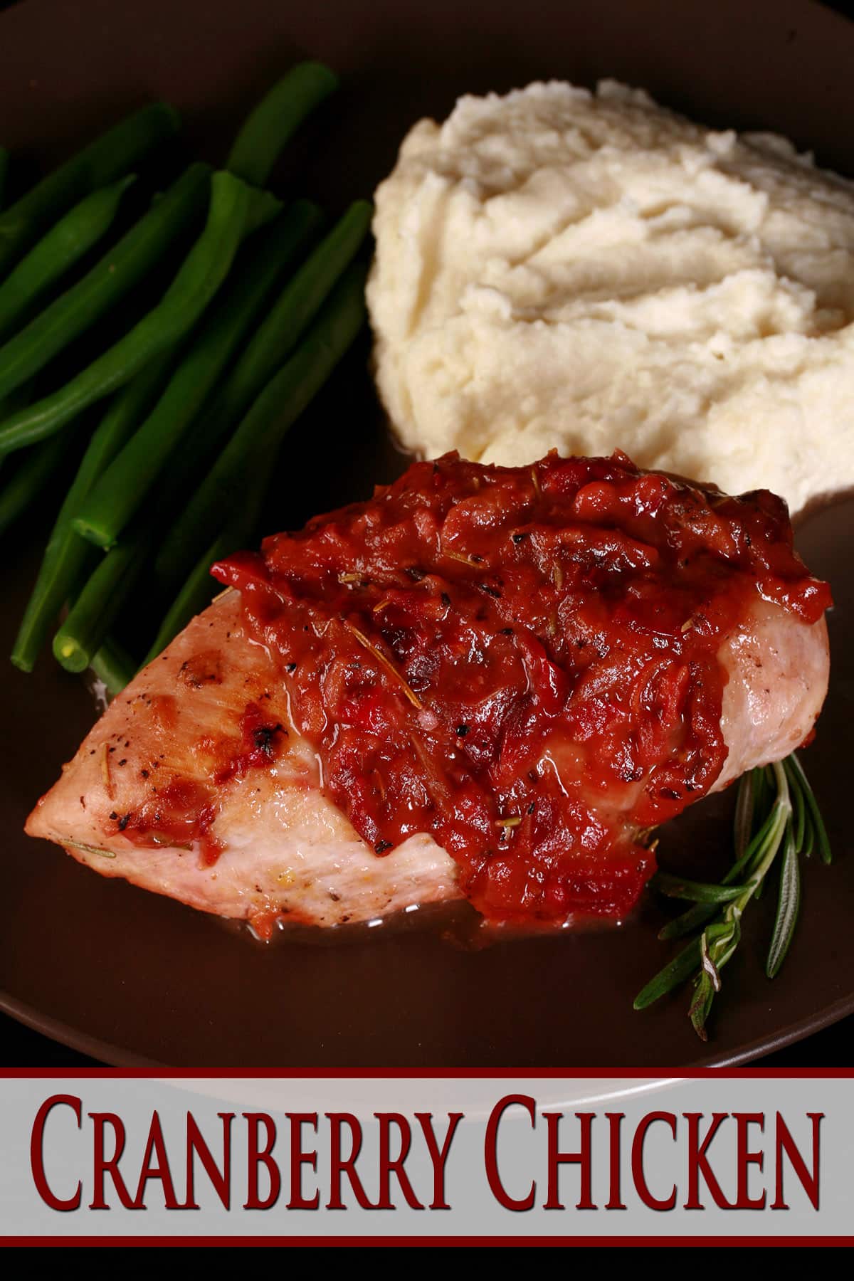 A serving of cranberry chicken on a plate with green beans and mashed cauliflower.