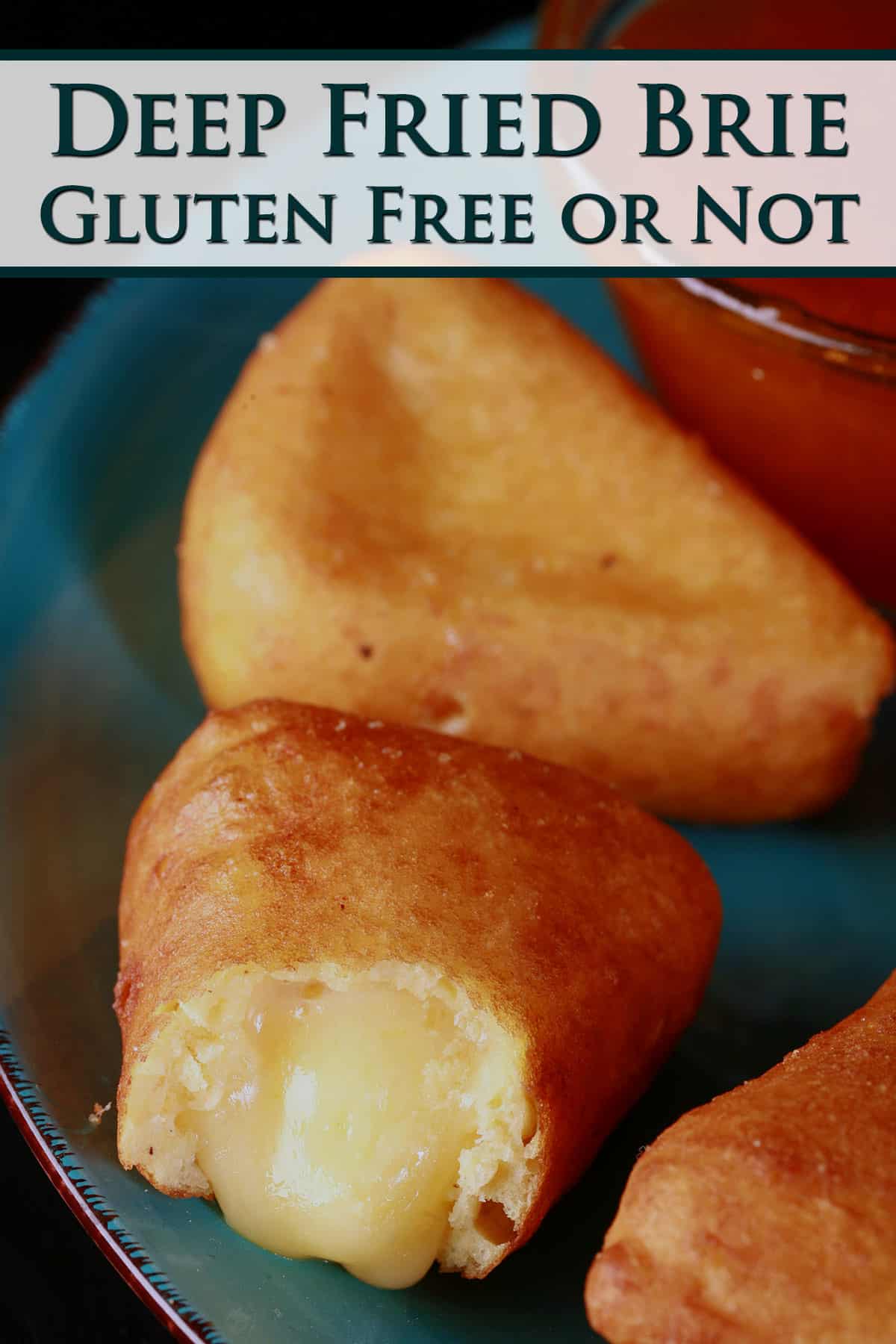 A plate of battered, deep fried brie cheese wedges, around a bowl of apricot preserves.  One has a bite, with brie oozing out.