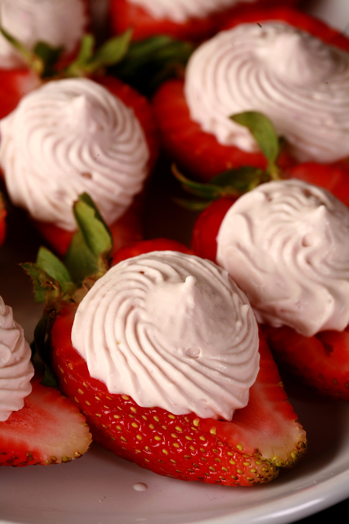 A white plate with deviled strawberries, filled with a cream cheese and balsamic vinegar whipped cream.