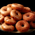 Close up view of gluten-free pumpkin spice mini doughnuts. Some are coated in cinnamon sugar, others are glazed with a tan coloured frosting.