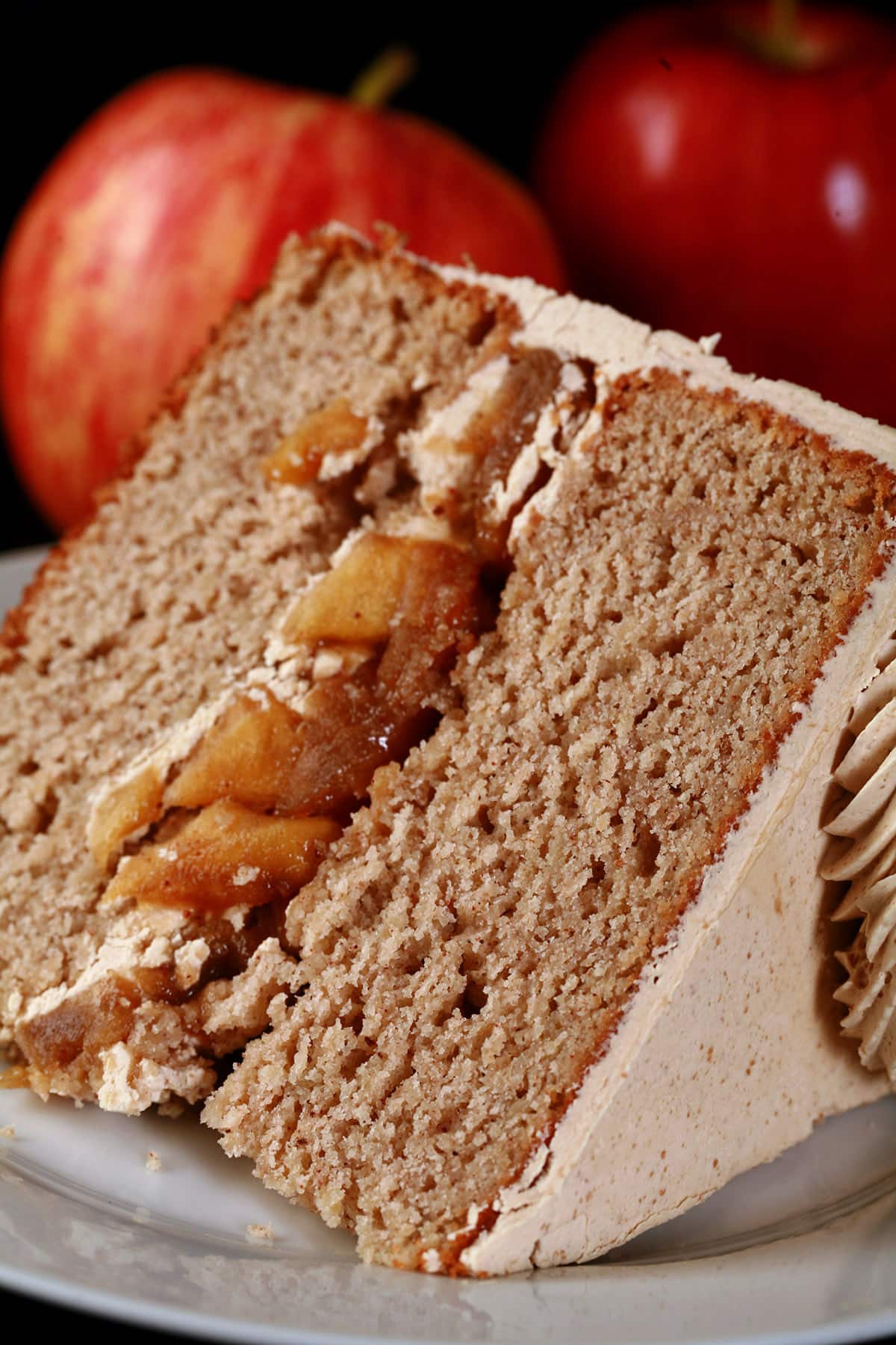 A slice of gluten-free apple cake, with apples in the background.