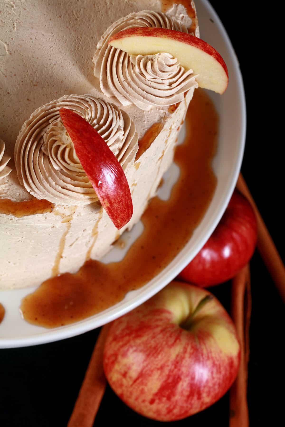 A close up photo of a whole gluten-free apple cake, garnished with syrup drizzle and apple slices.