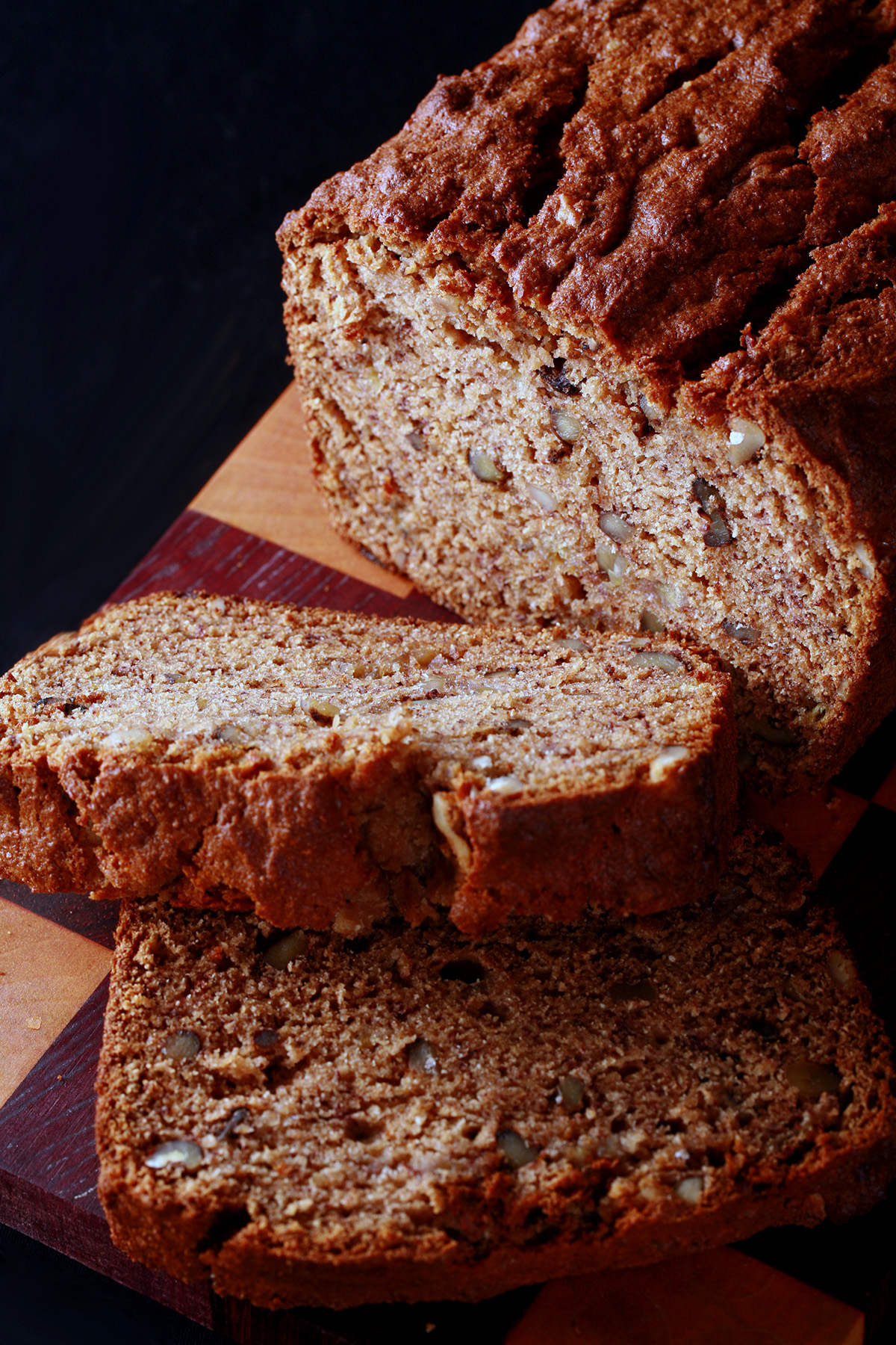 A loaf of gluten free banana bread, along with 2 slices cut from it.