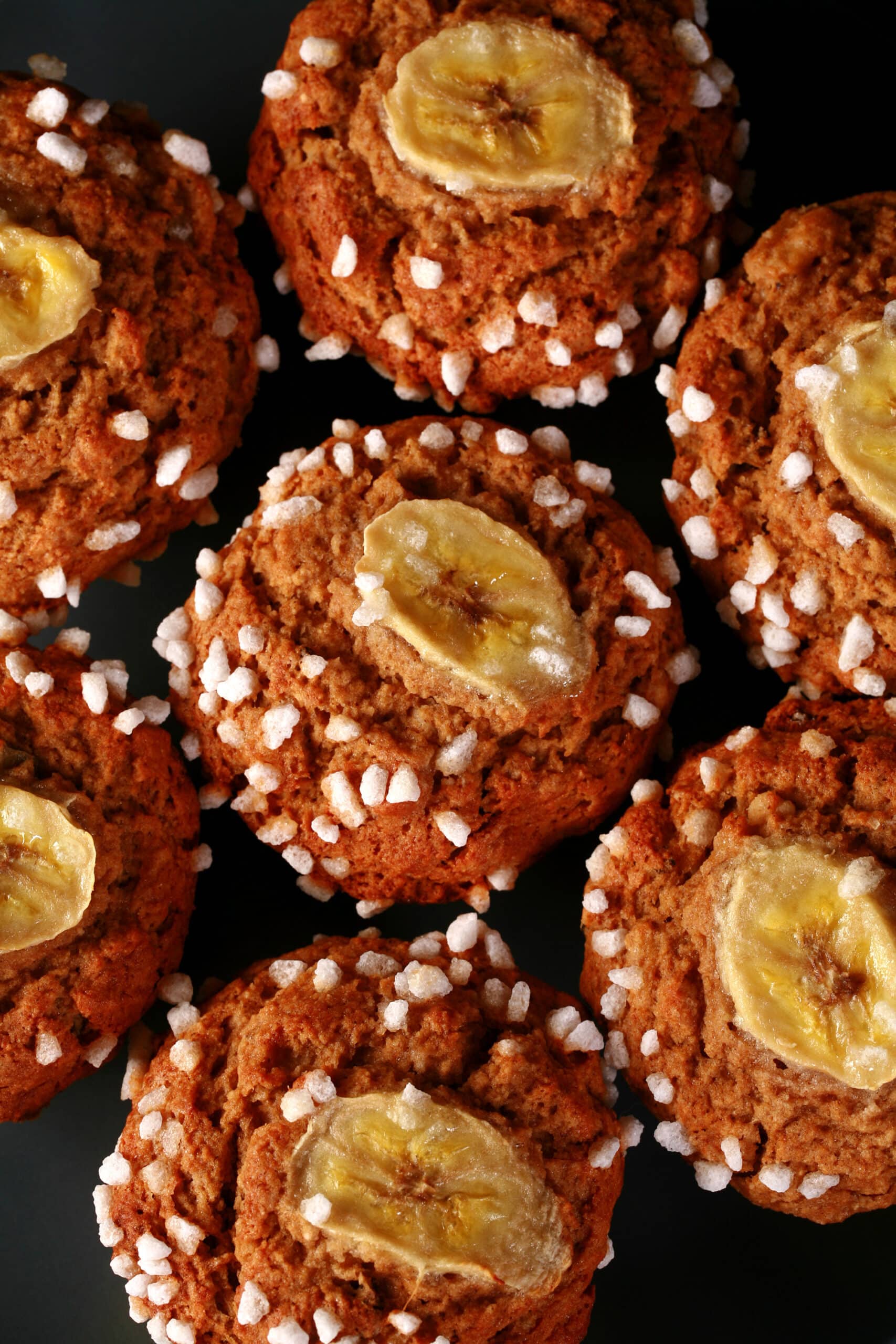 A plate of gluten free banana muffins, topped with coarse sugar and banana slices.