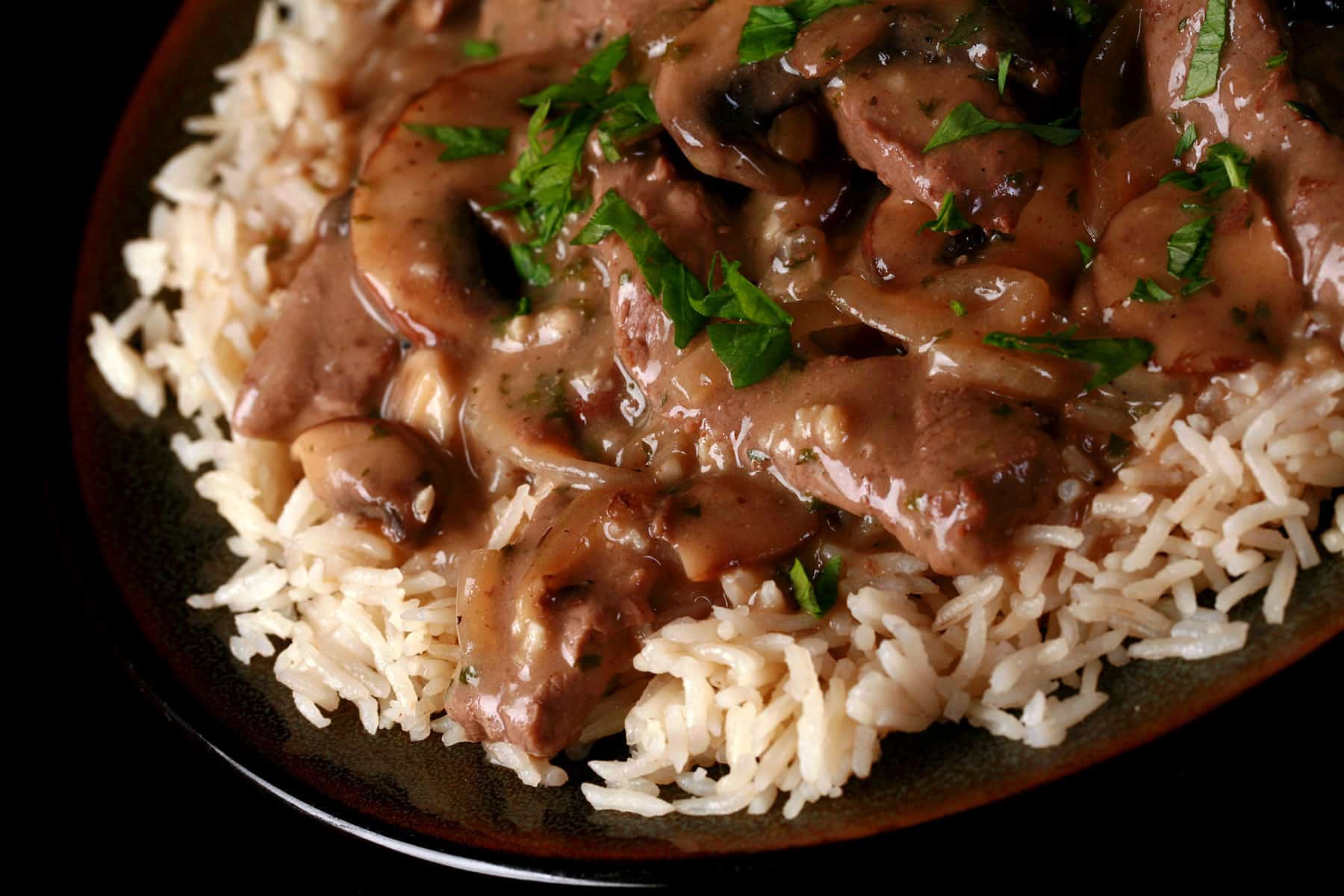 A serving of gluten free beef stroganoff over a bed of rice.