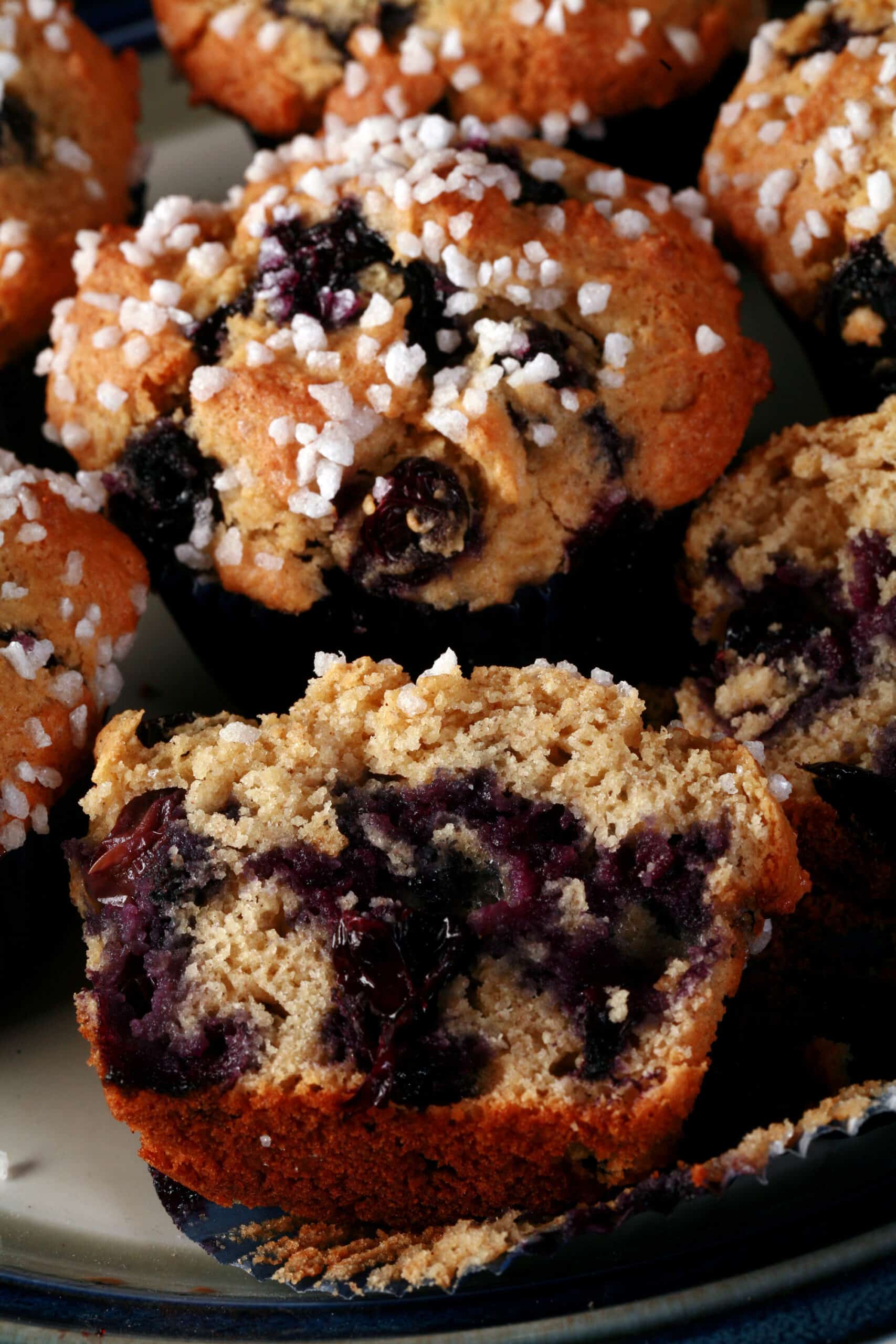 Several sugar topped gluten free blueberry muffins on a plate.