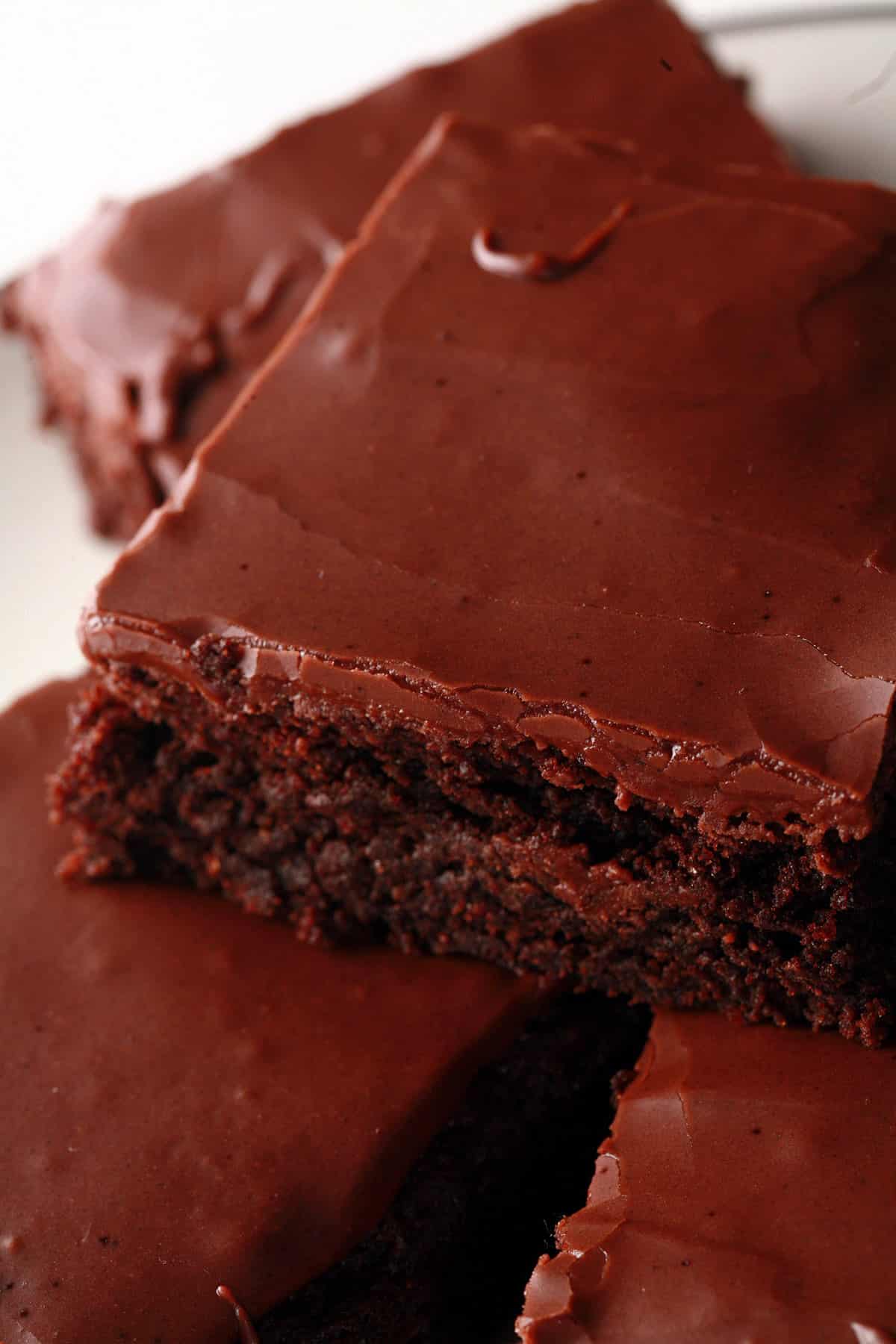 A plate of gluten-free brownies with chocolate glaze.