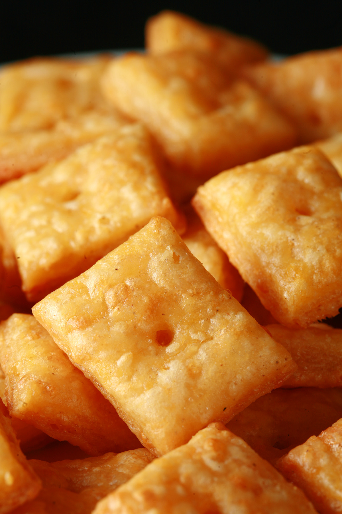 A pile of gluten-Free Cheez-its - little square gluten-free cheese crackers.