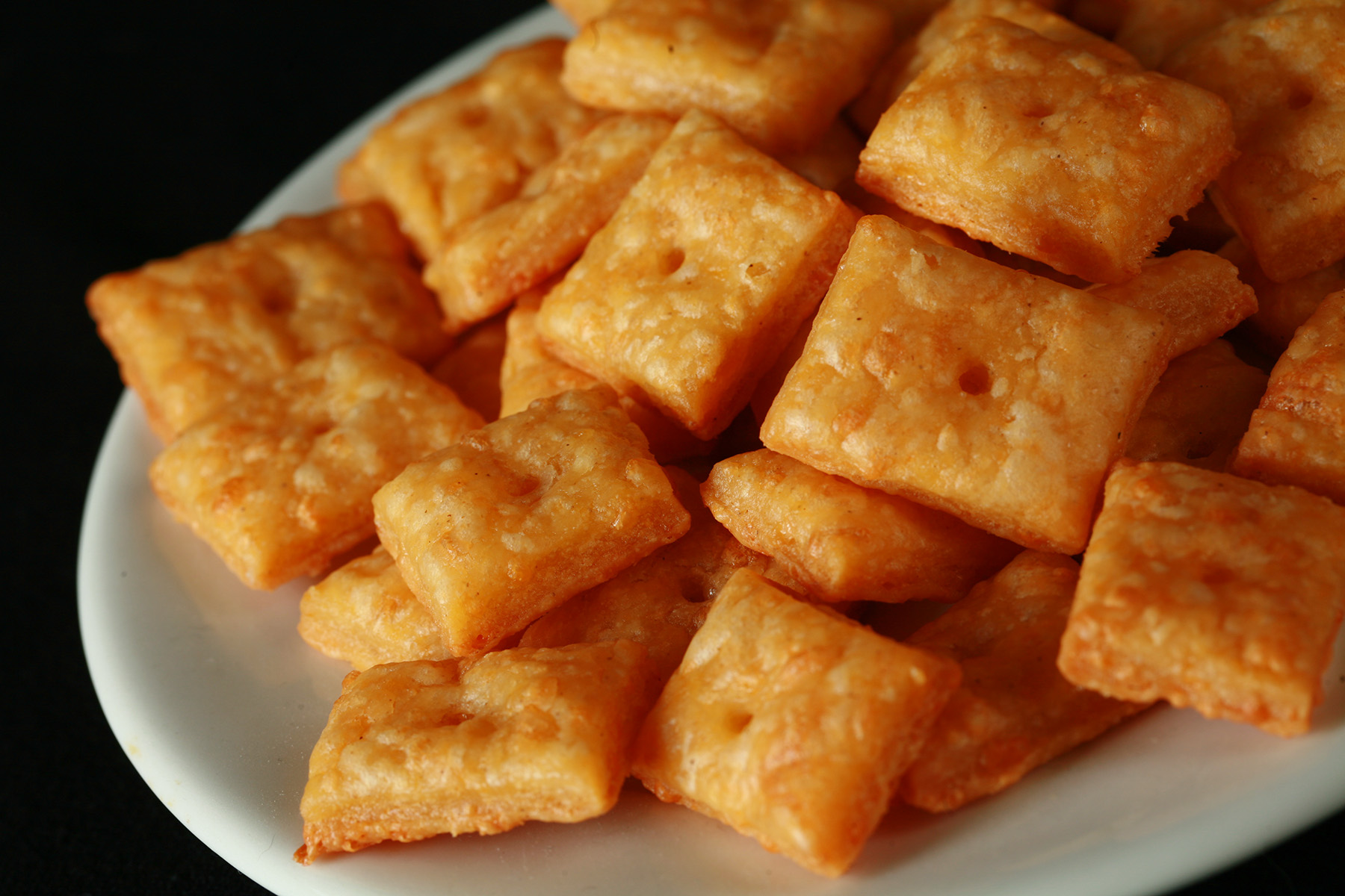 A pile of gluten-Free Cheez-its - little square gluten-free cheese crackers.