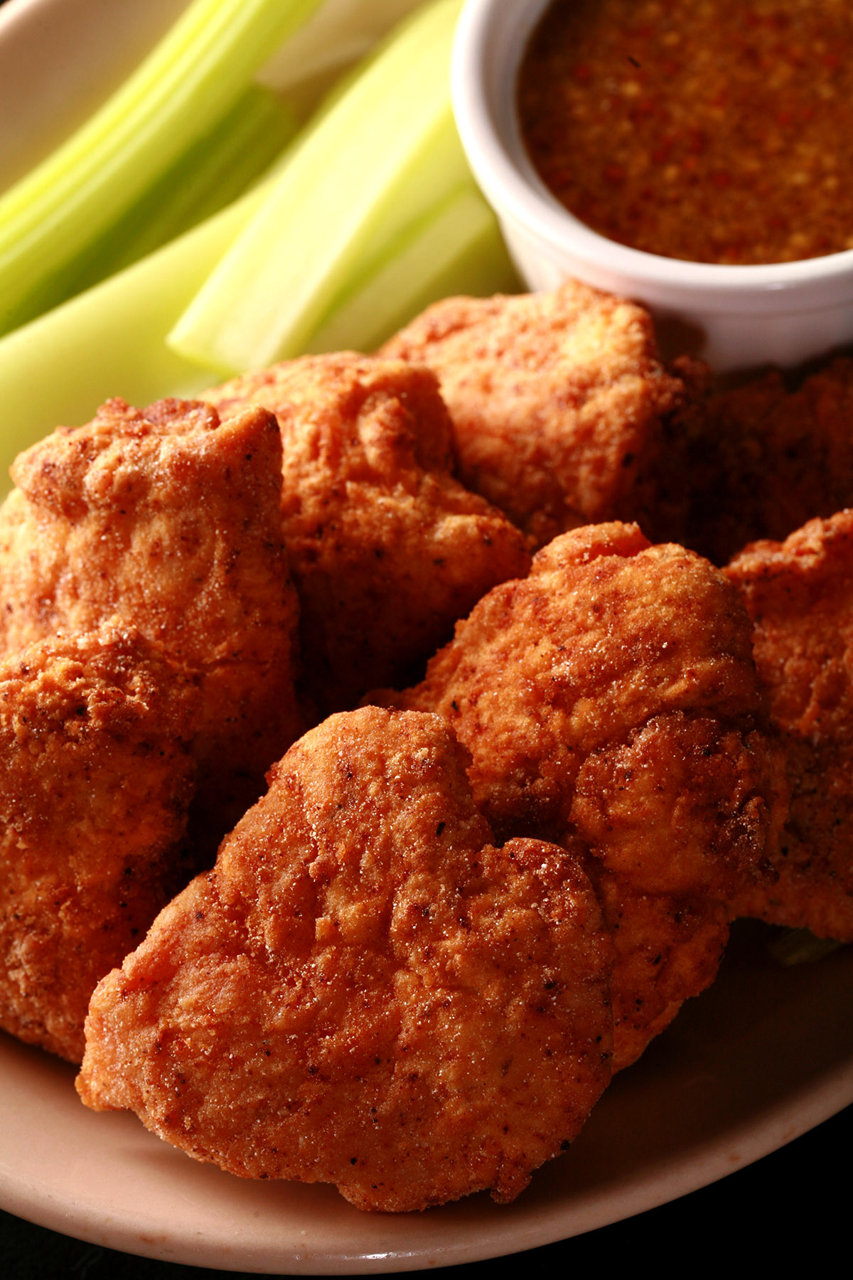 A plate of deep fried gluten free chicken nuggets, celery, and dip.