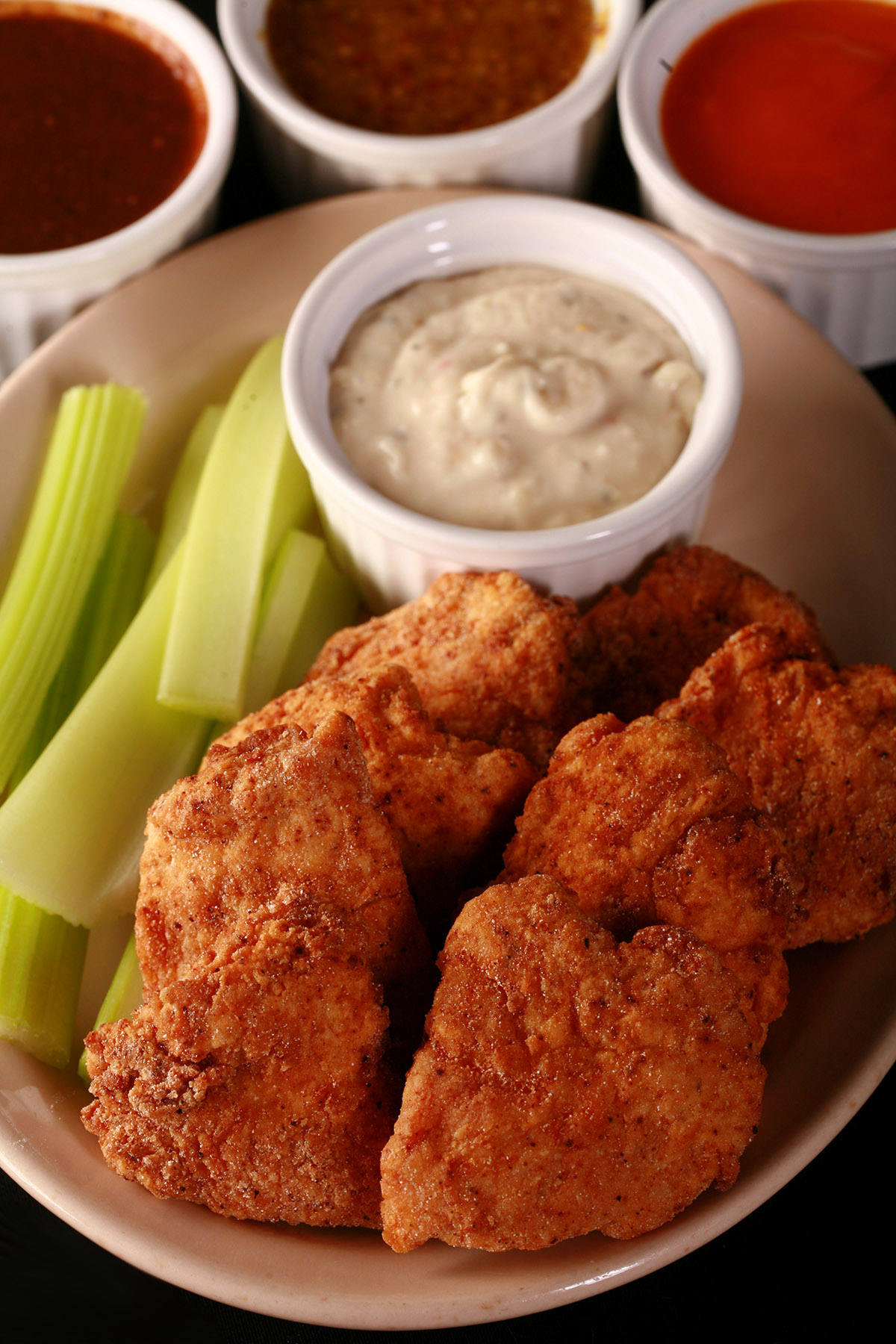 A plate of deep fried gluten-free chicken nuggets, celery, and dip.