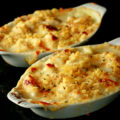 Two oblong ceramic ramekins of gluten-free cod au gratin. Cod is in a creamy, cheesy sauce, topped with crushed chips, more cheese, and savoury.