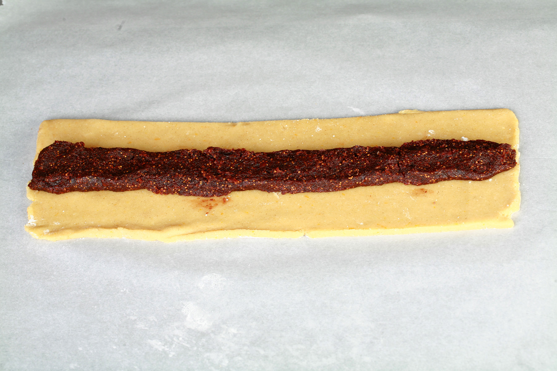 A long, narrow strip of fig newton dough with a long, narrow strip of filling down the middle of it.