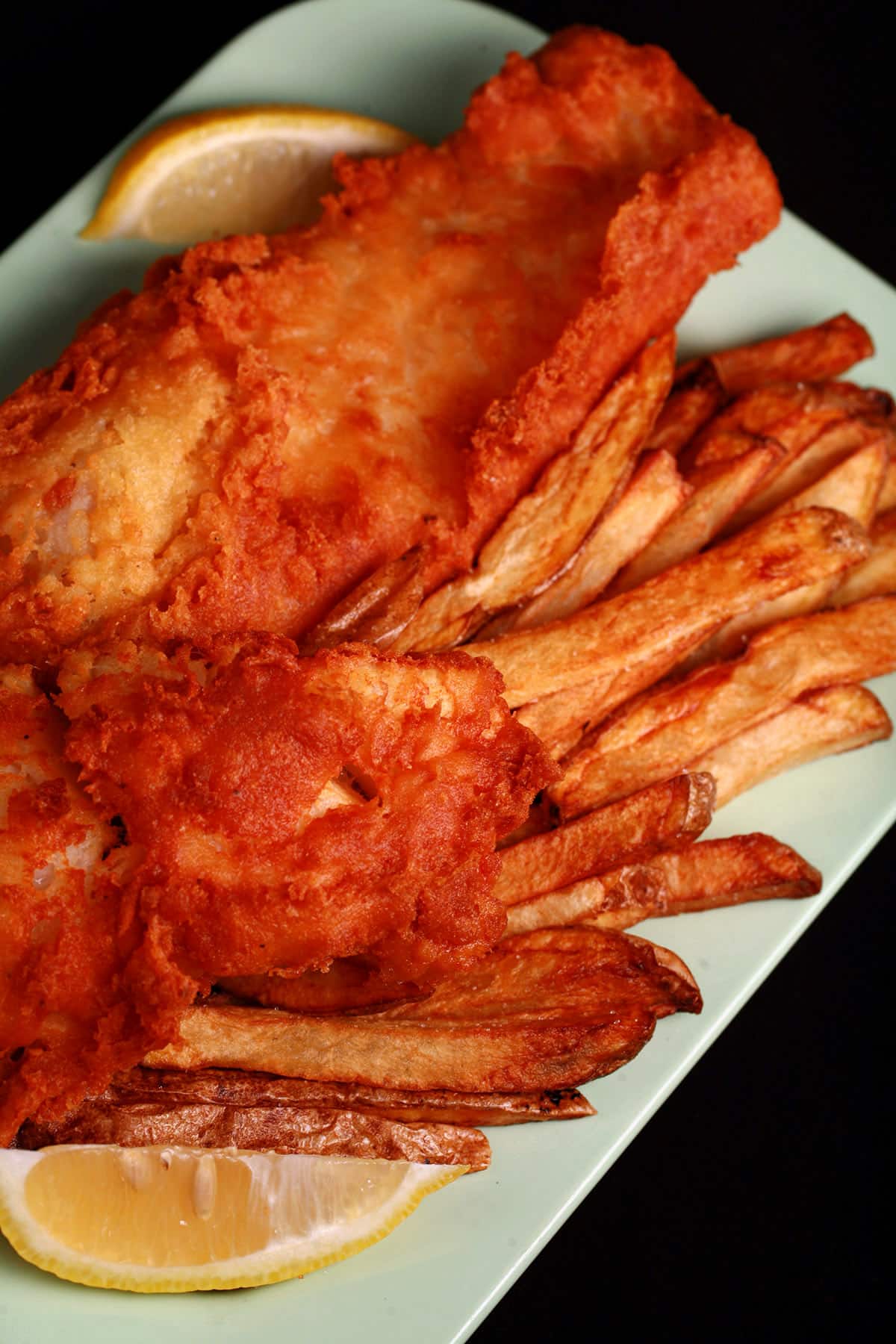 A plate of gluten-free fish and chips, with a wedge of lemon.