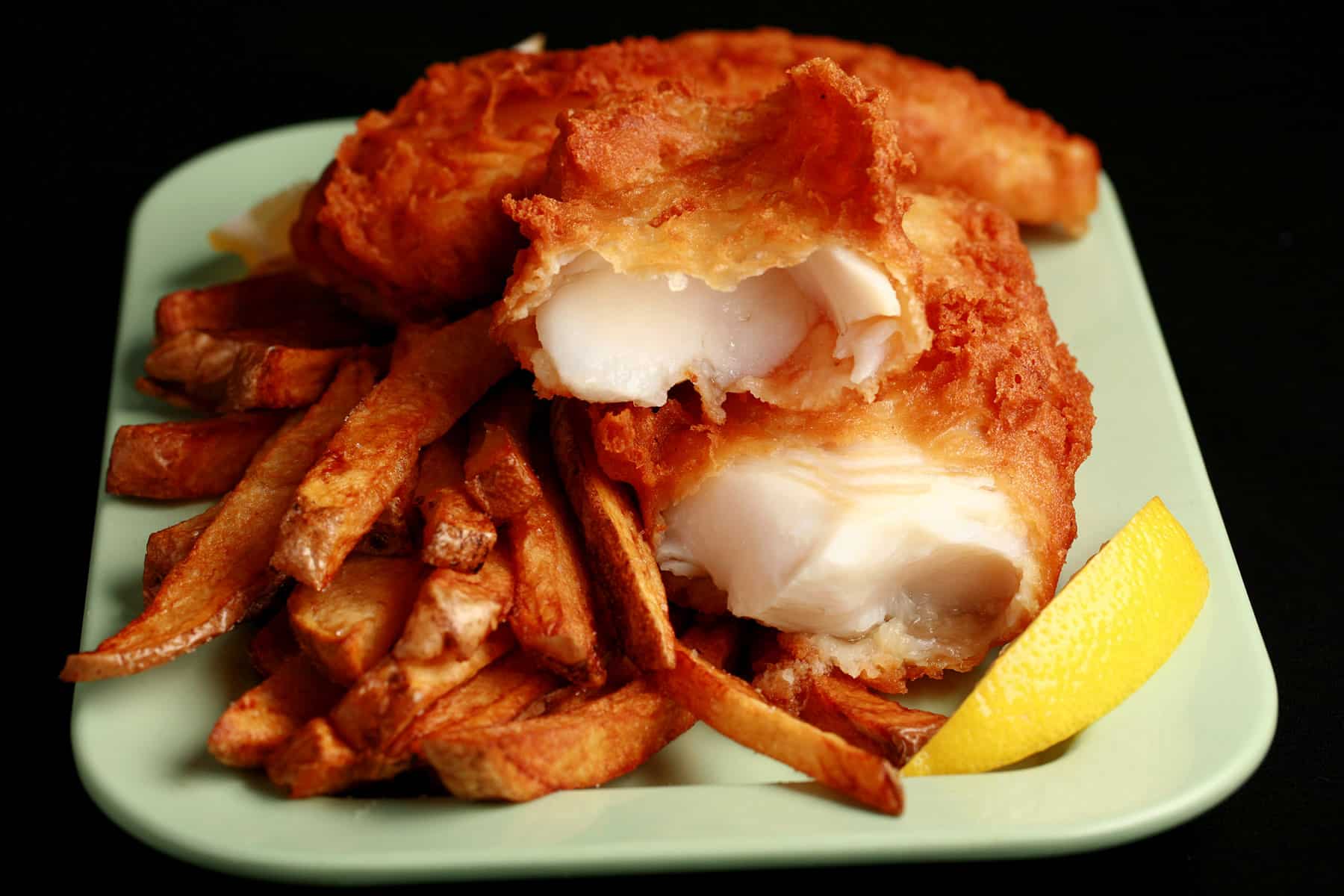 A plate of gluten free fish and chips, with a wedge of lemon.