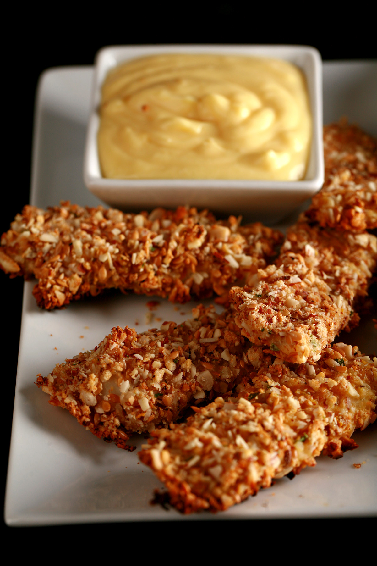 A plate of gluten-free fish fingers with a small bowl of savoury custard on the plate.