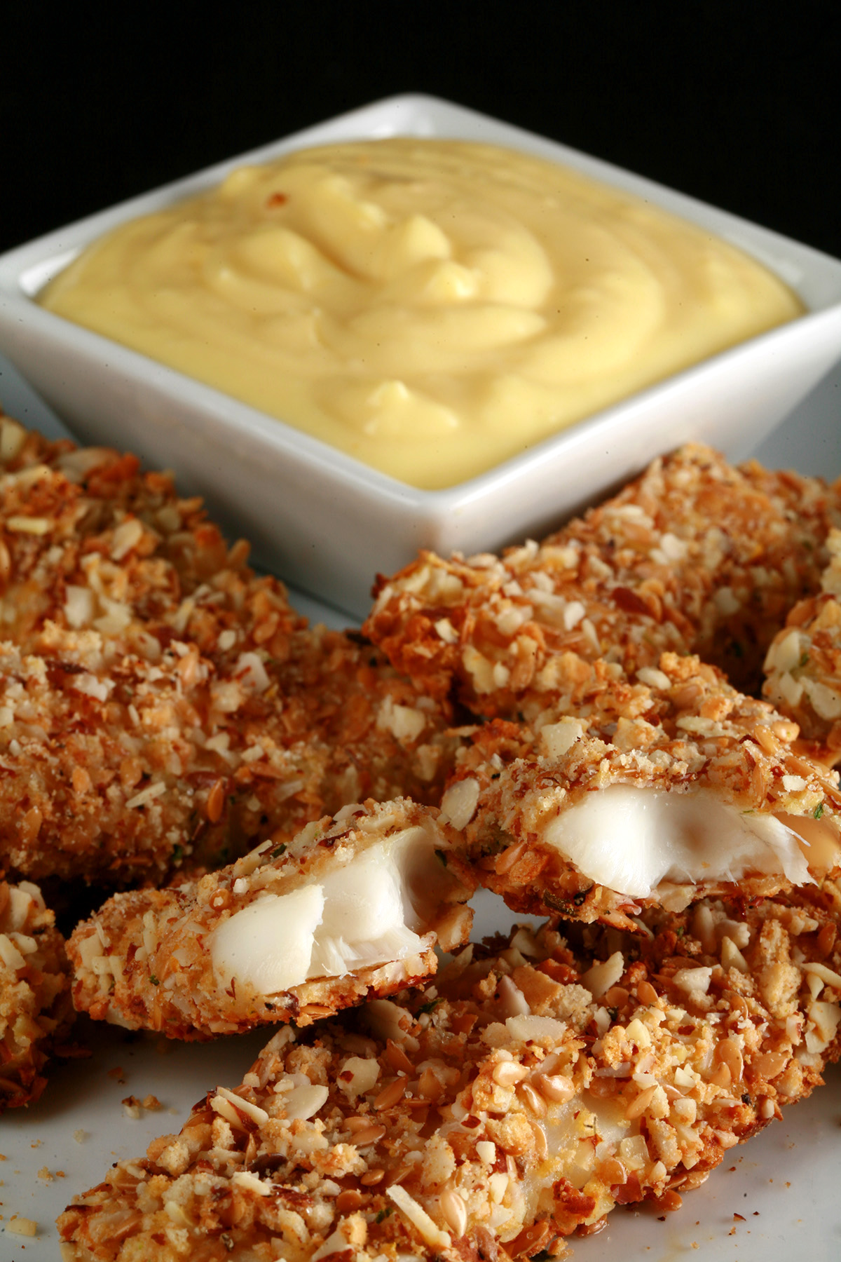 A plate of gluten-free fish fingers with a small bowl of savoury custard on the plate.
