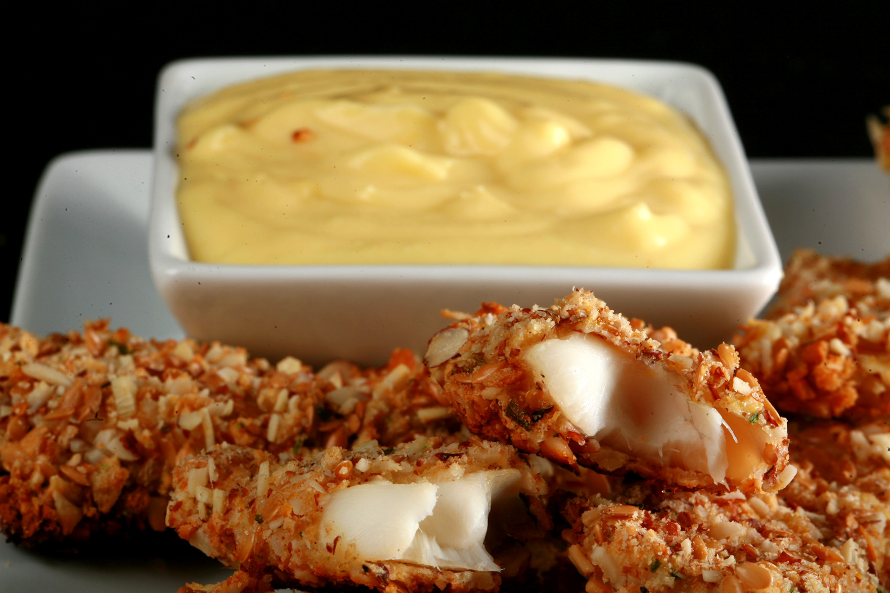 A plate of gluten-free fish fingers with a small bowl of savoury custard on the plate.