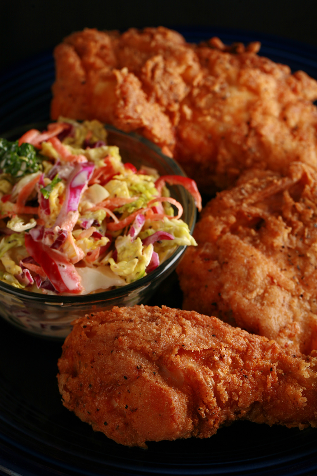 3 pieces of gluten-free fried chicken on a plate, next to a small bowl of colourful coleslaw.