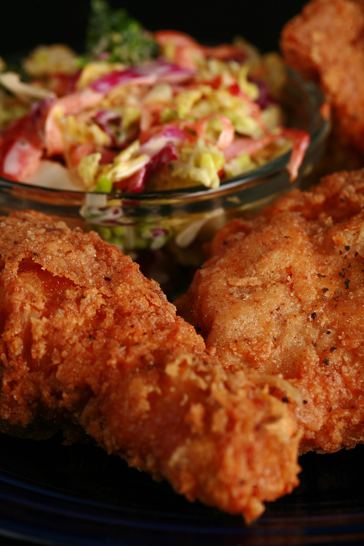 3 pieces of gluten-free fried chicken on a plate, next to a small bowl of colourful coleslaw.