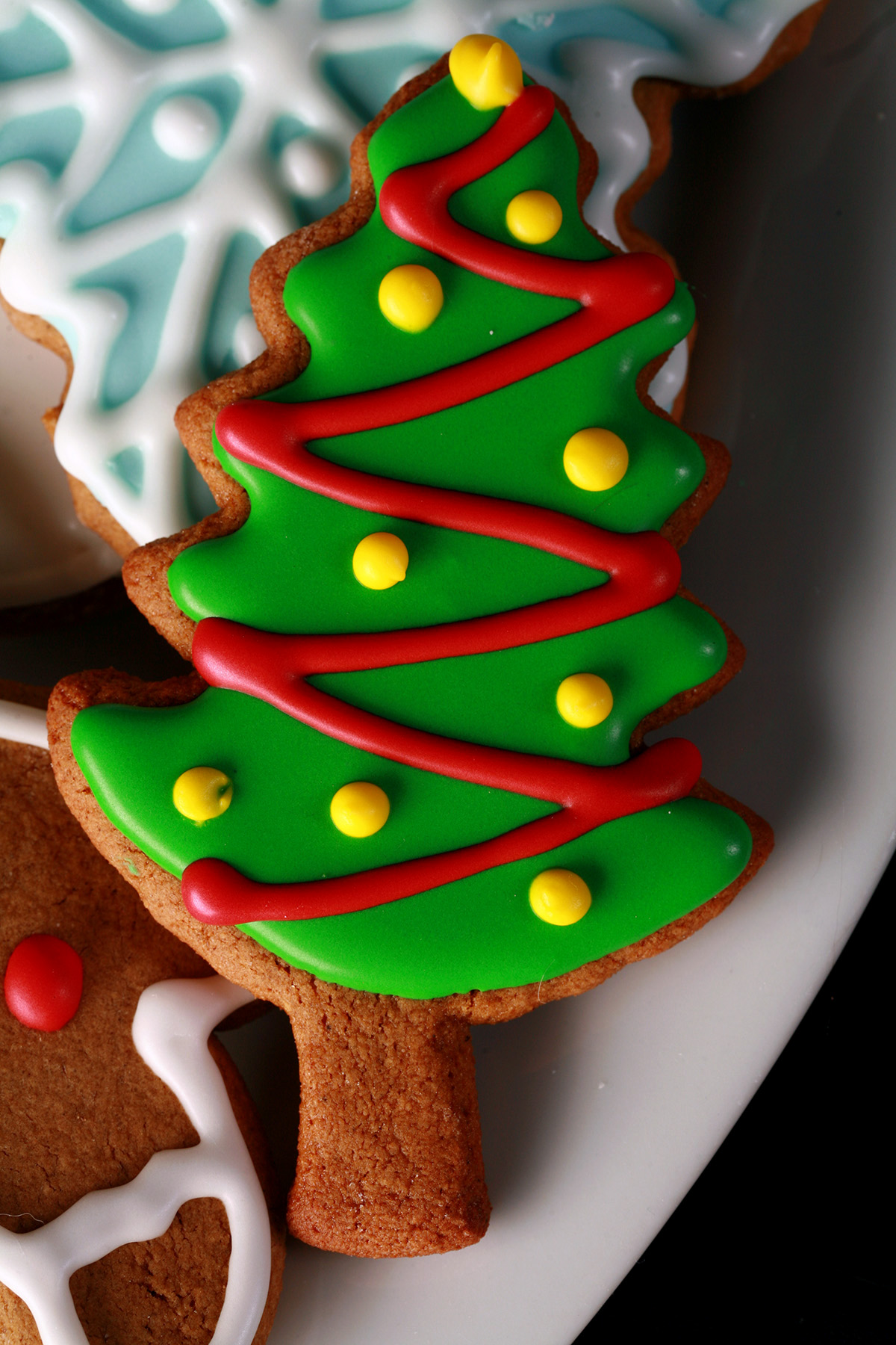 A plate of gluten-free gingerbread cookies, in various shapes, decorated with colourful royal icing.