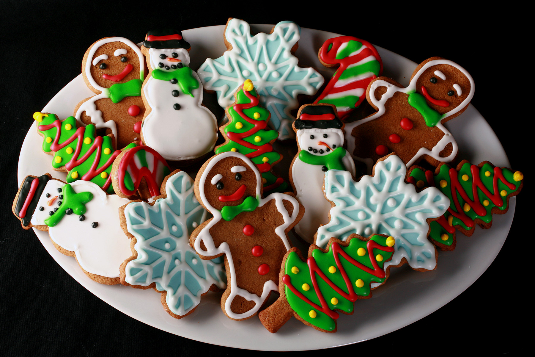 A plate of gluten-free gingerbread cookies, in various shapes, decorated with colourful royal icing.