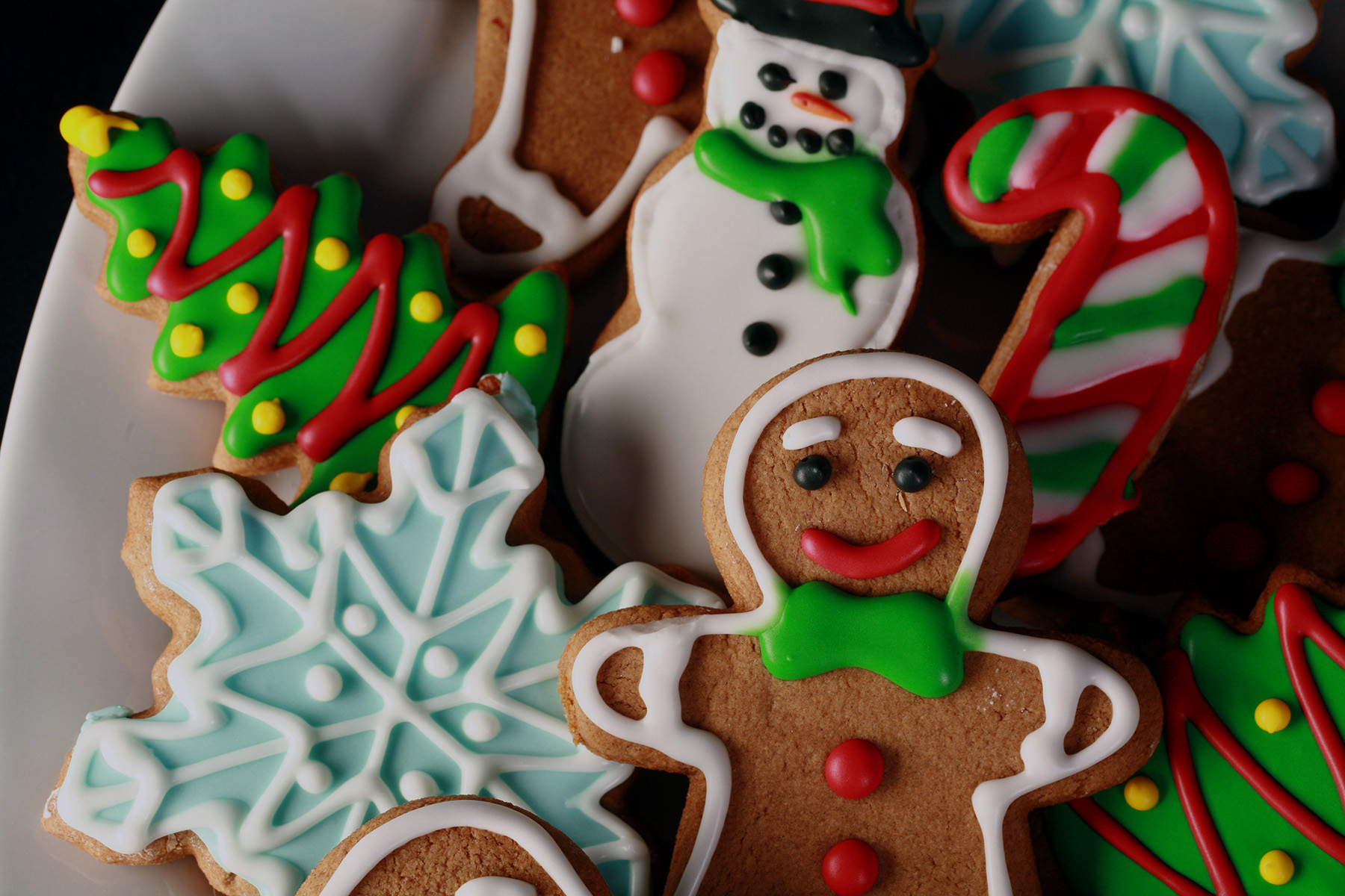 A plate of gluten-free gingerbread cookies, in various shapes, decorated with colourful royal icing.