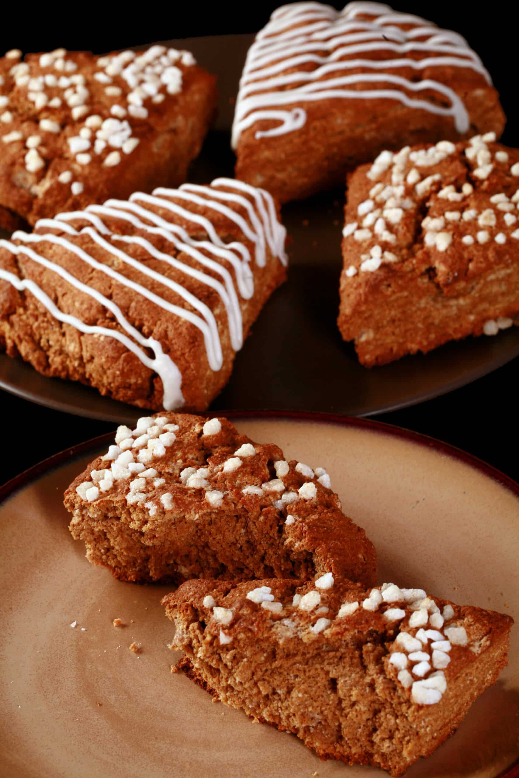 A plate of gluten-free gingerbread scones. Half have a sugar crust, the other half have a vanilla glaze drizzled over them.