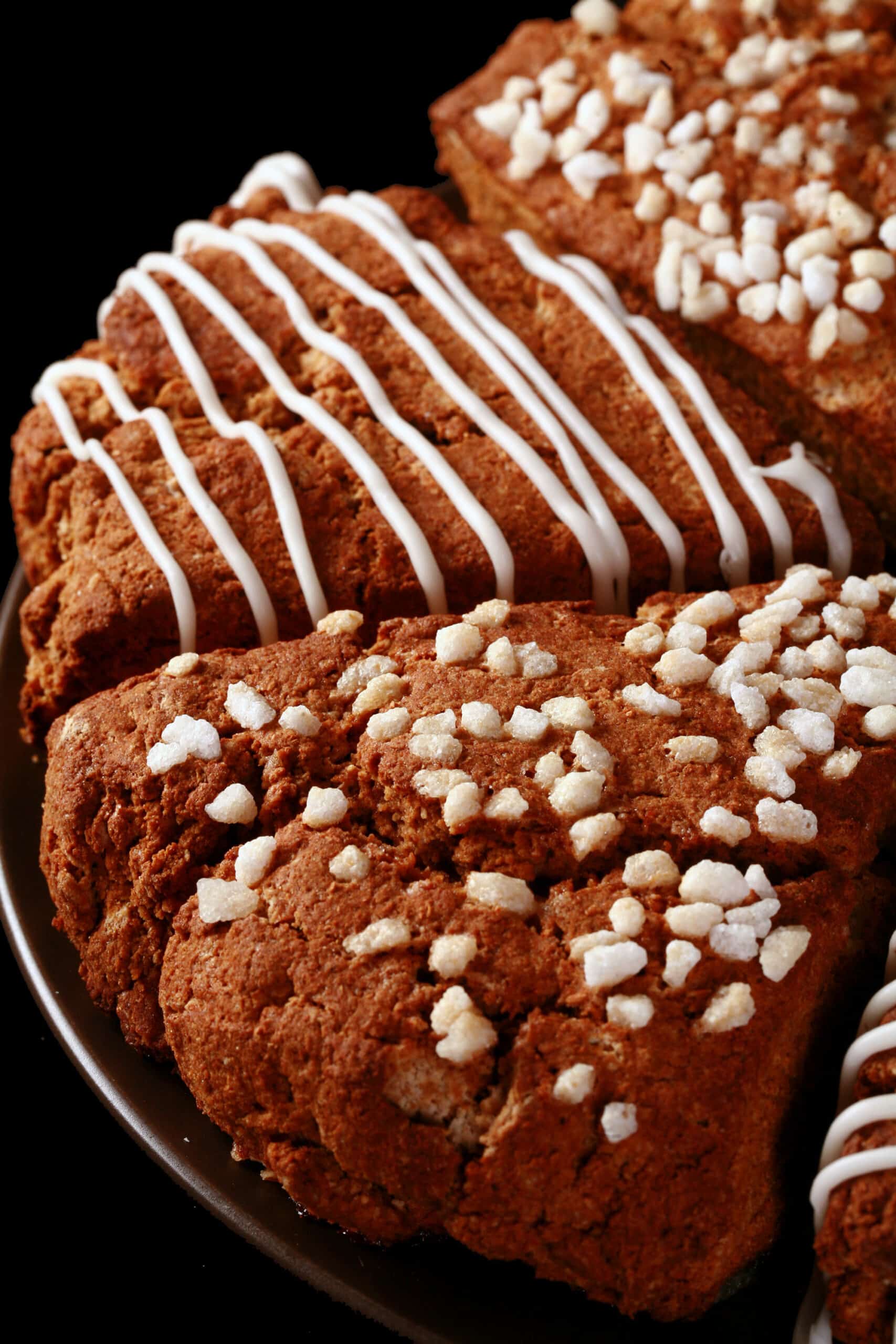 A plate of gluten free gingerbread scones. Half have a sugar crust, the other half have a vanilla glaze drizzled over them.