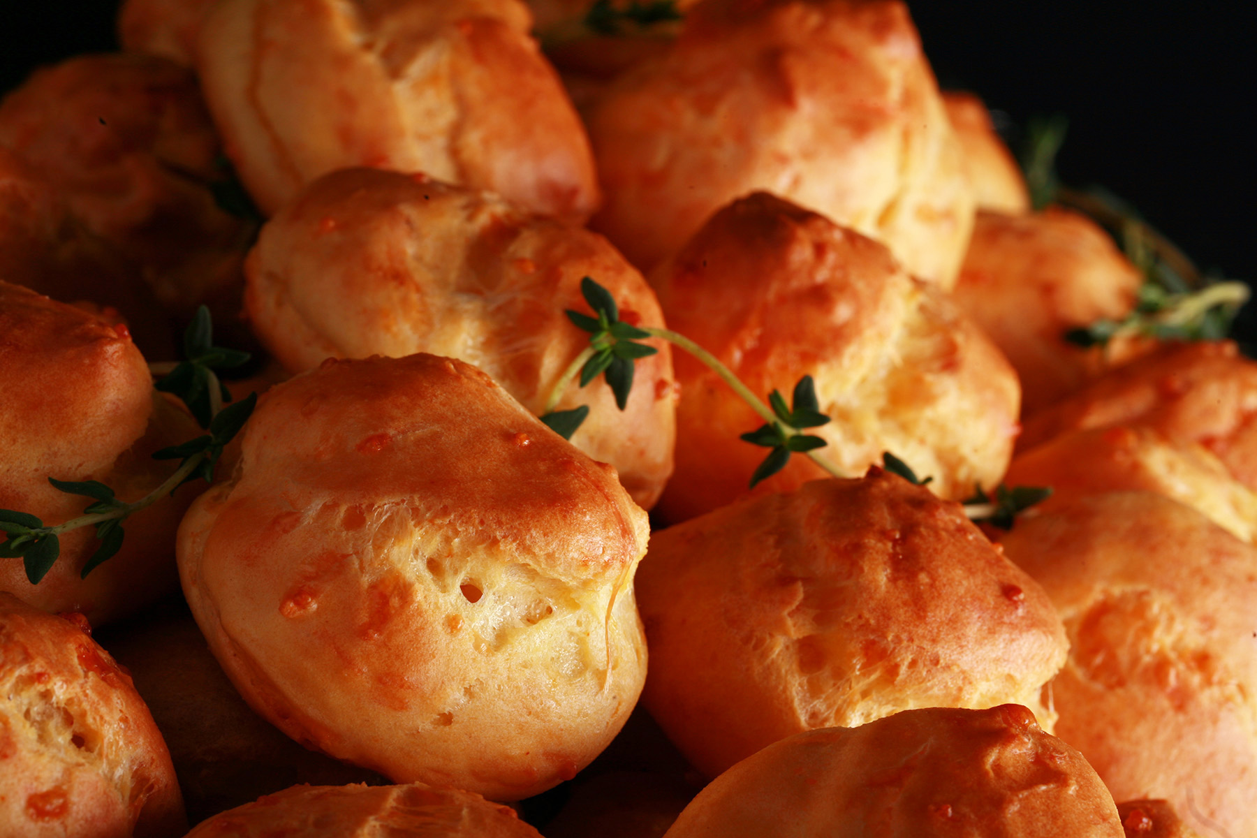 A large pile of Gluten-free Cheese Puffs - small, cheesy pastries - on a silver plate.