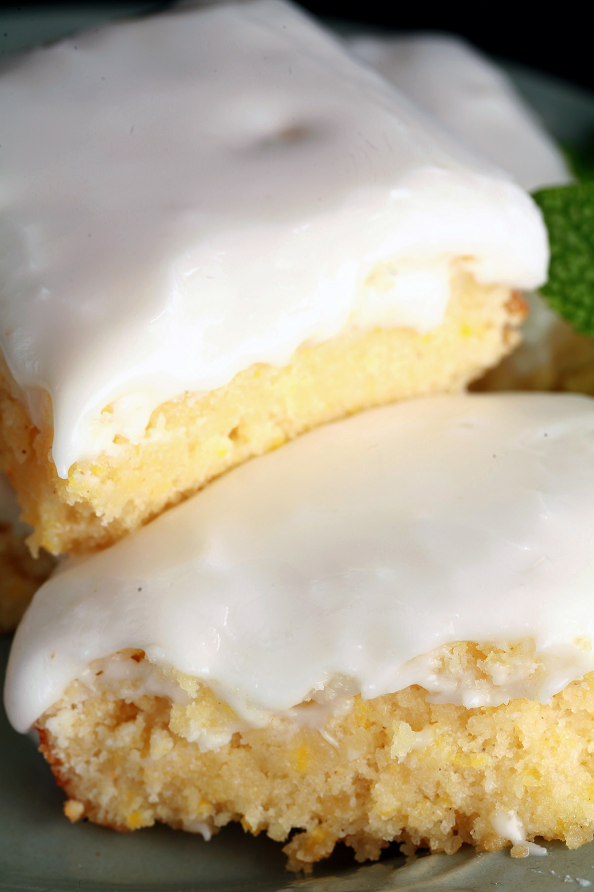 A plate of frosted chewy gluten-free lemon bars, garnished with mint leaves.