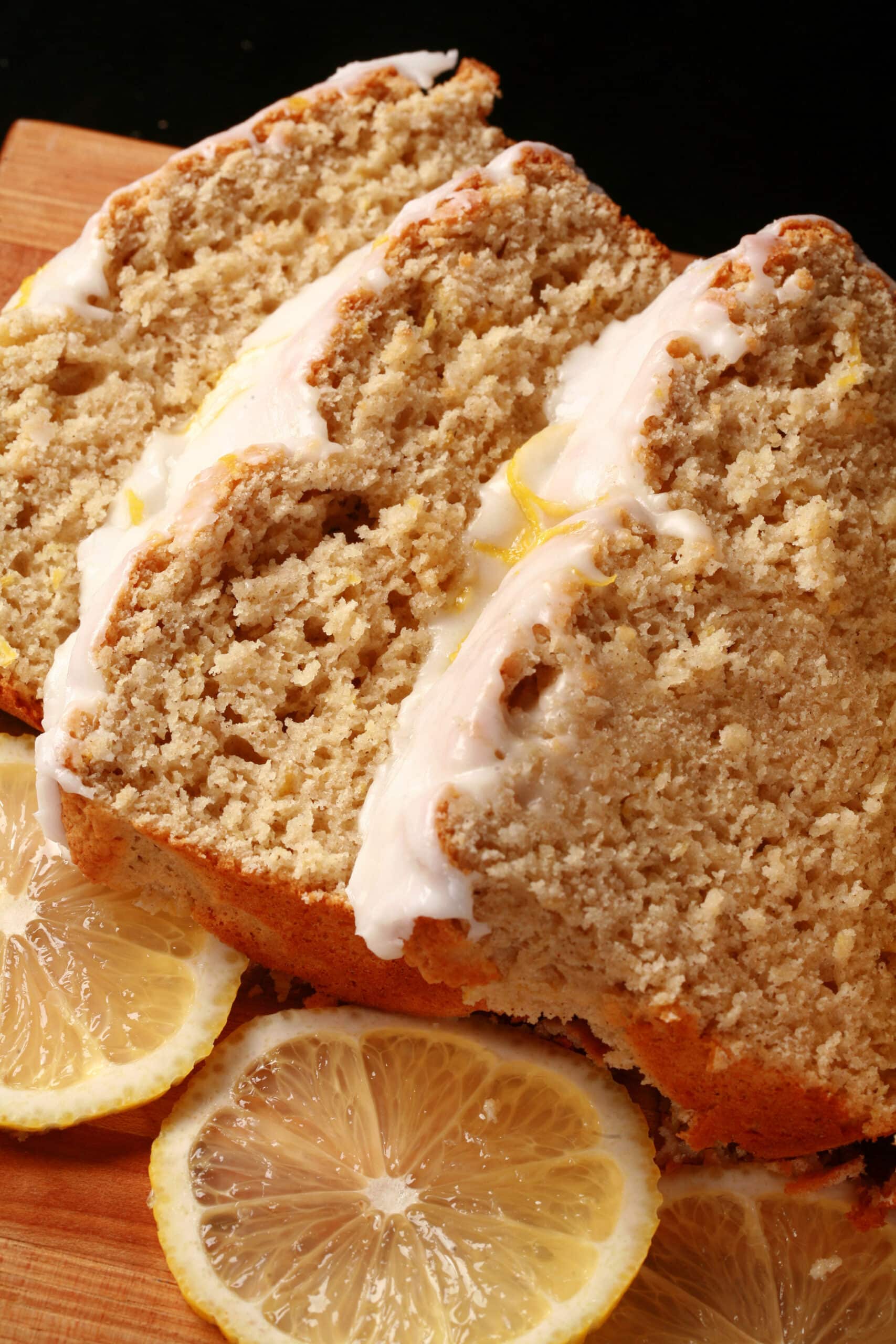 A sliced loaf of gluten free lemon loaf, with white glaze and lemon zest on top.