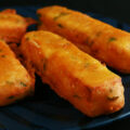 Several sticks of gluten-free paneer pakora - deep fried cheese sticks - on a blue plate.