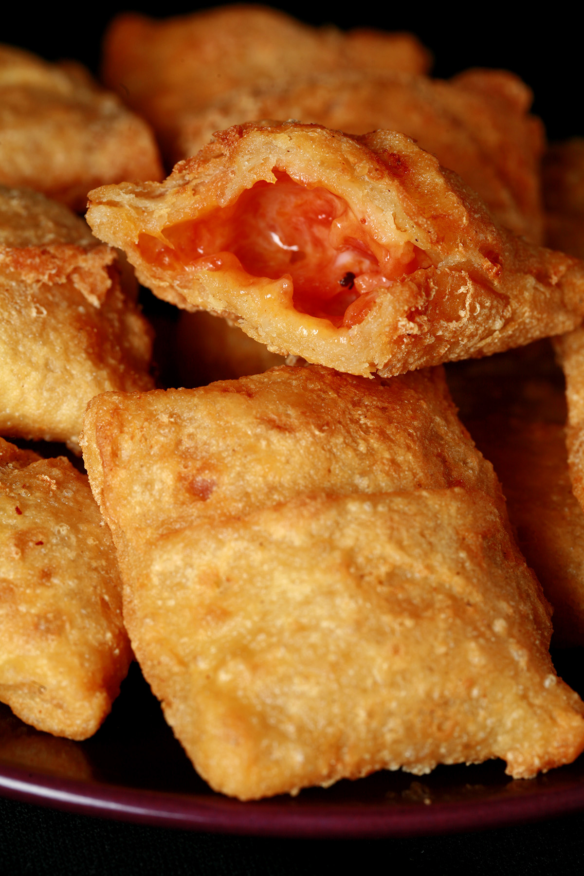 A plate with a pile of gluten-free pizza bites. One has been cut in half to show its pizza filling.