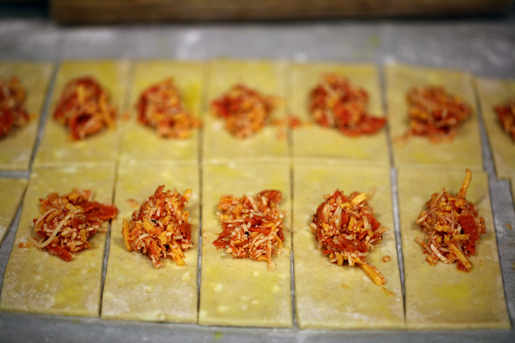 Dough that has been rolled out, cut into thin strips, and topped with a small mound of filling.