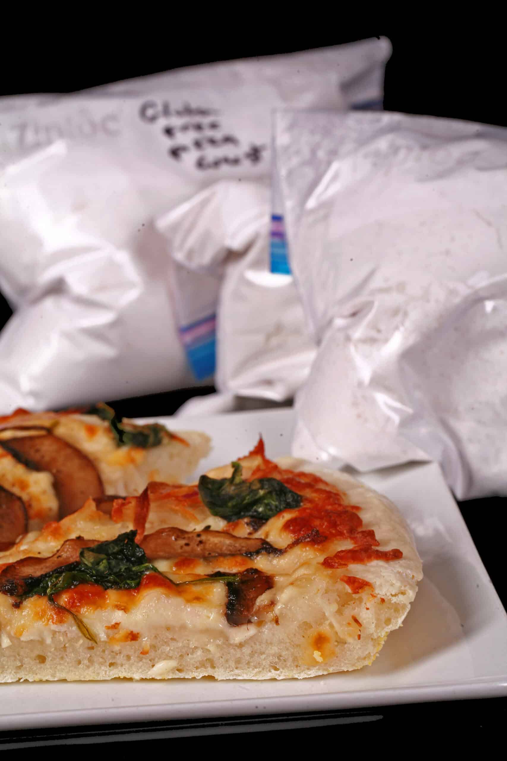 Several freezer bags of homemade gluten free pizza dough mix, with baked pizza on a plate.