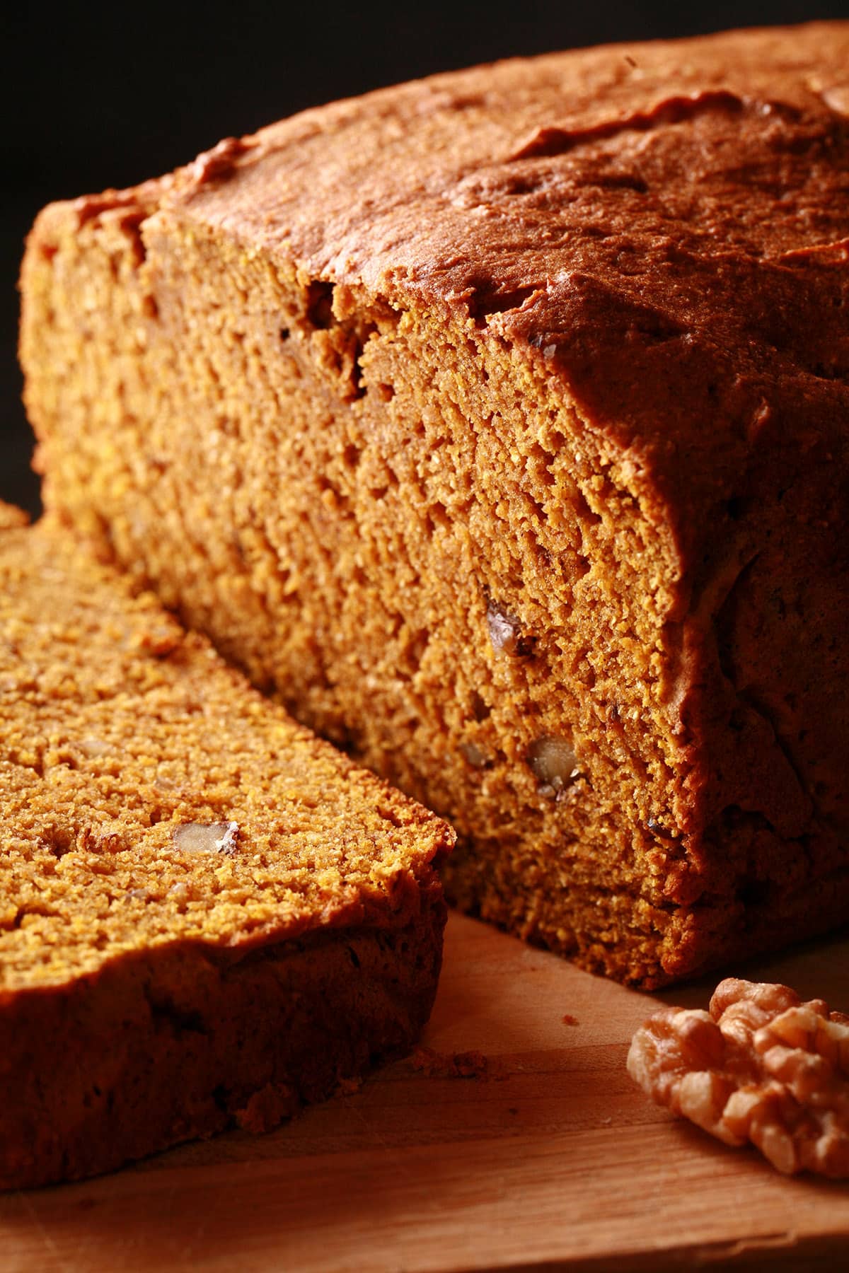 A loaf of gluten free pumpkin bread on a cutting board, sliced.