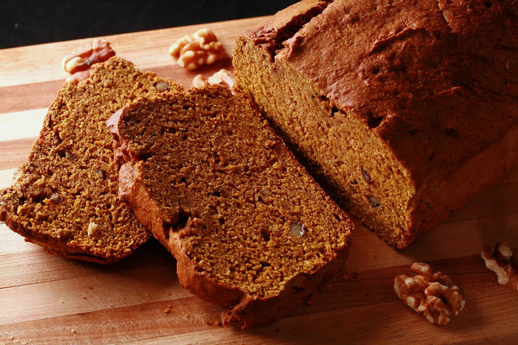 A loaf of gluten-free pumpkin bread on a cutting board, sliced.