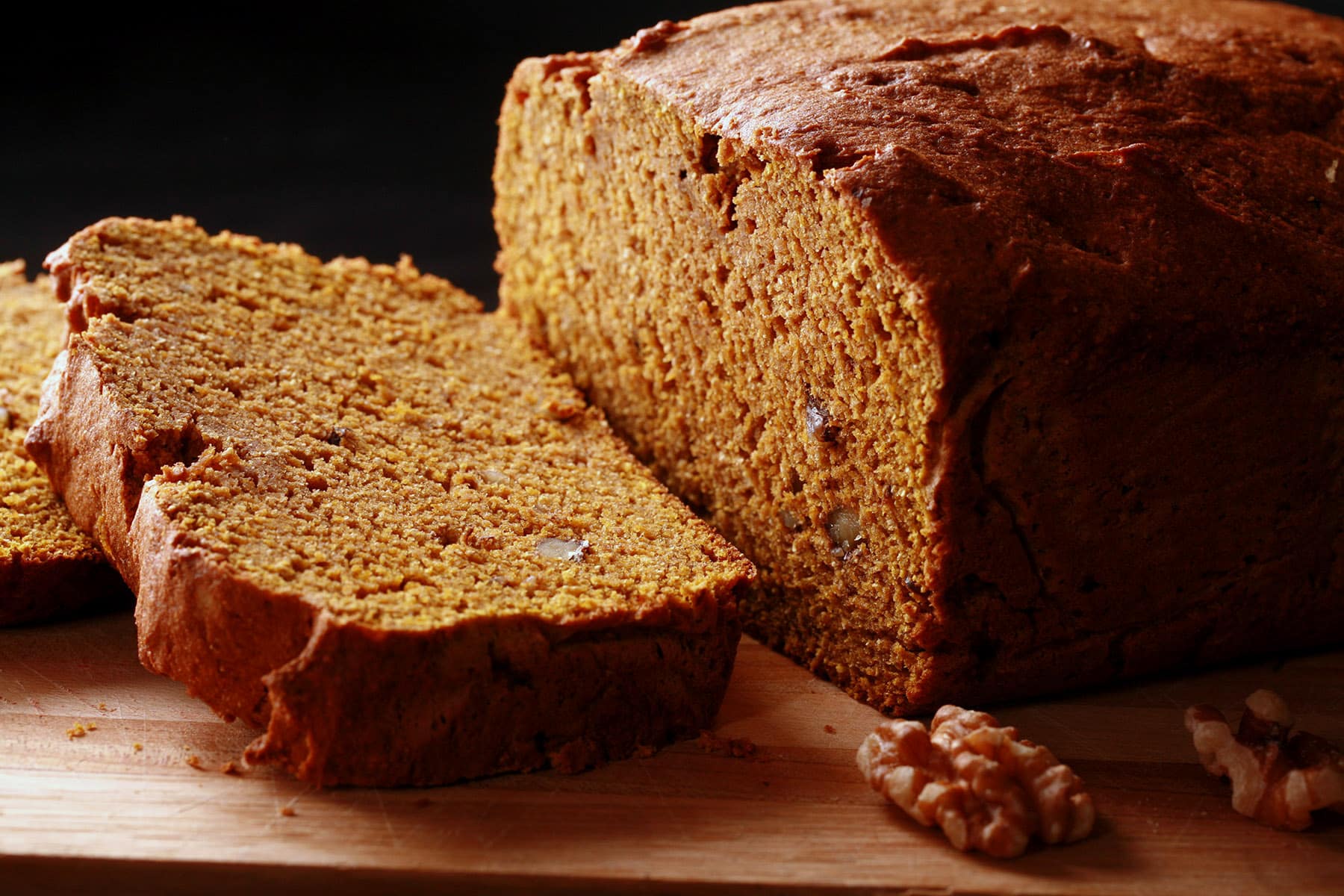 A loaf of gluten-free pumpkin spice bread on a cutting board, sliced.