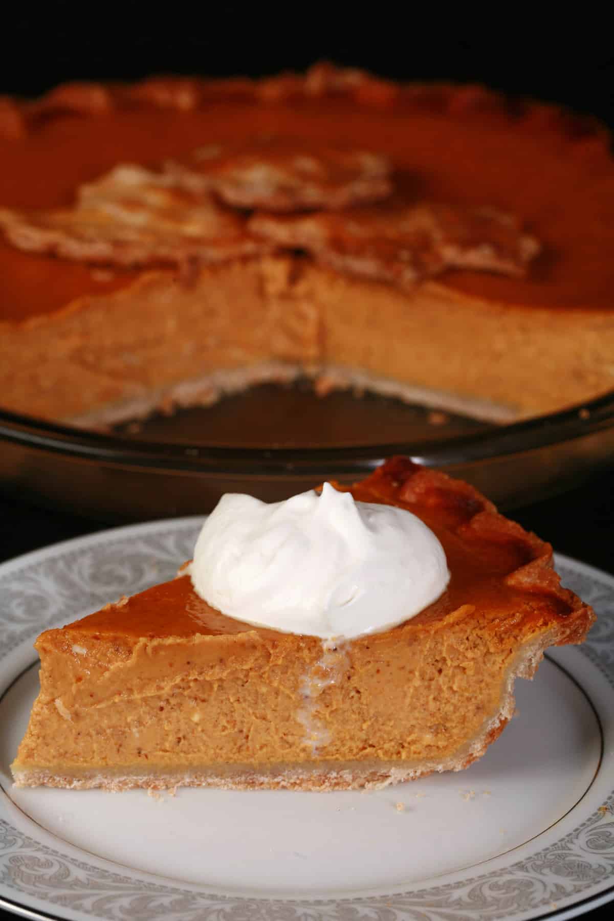A slice of gluten-free pumpkin pie topped with maple whipped cream.