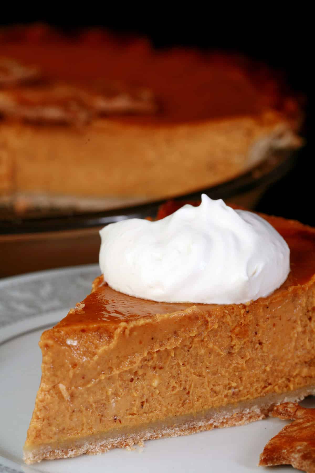 A slice of gluten-free pumpkin pie topped with maple whipped cream.