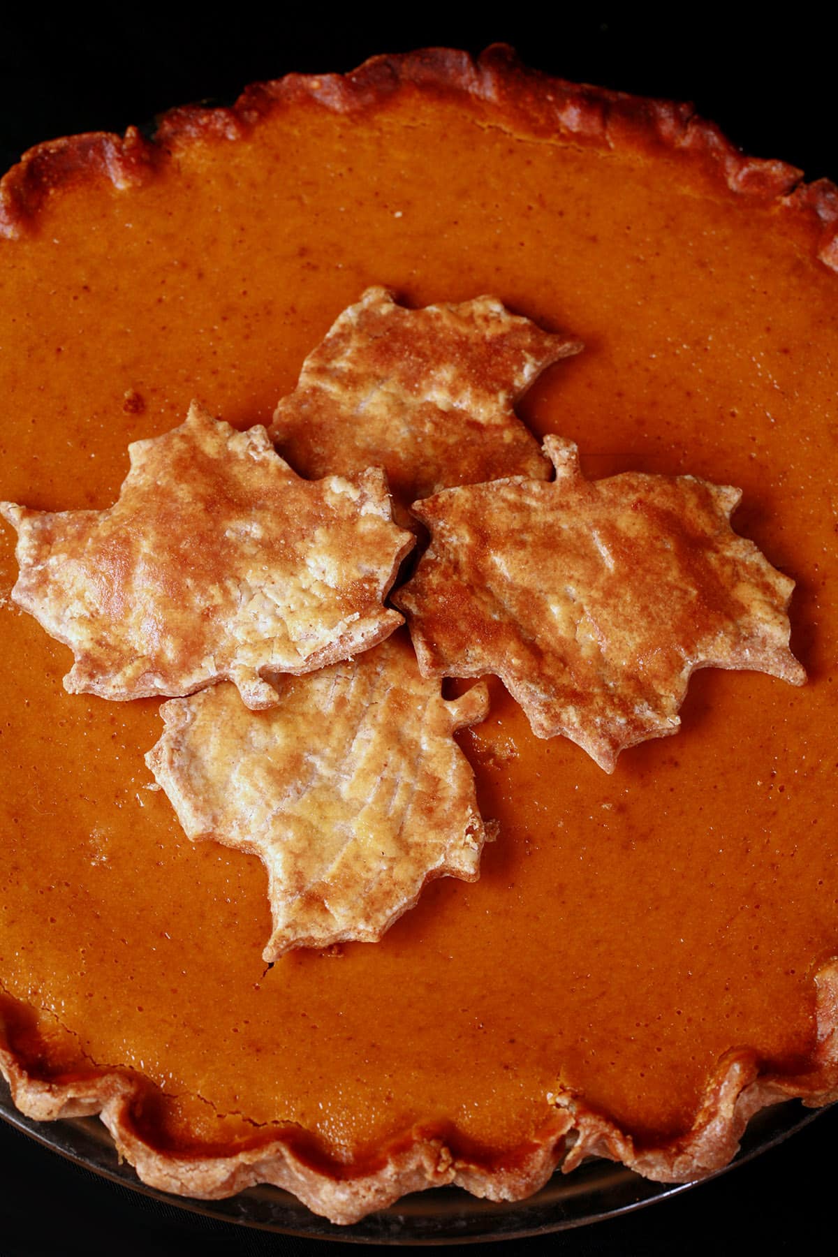 A close up view of the top of a gluten free pumpkin pie, topped with gluten-free pie crust maple leaves.