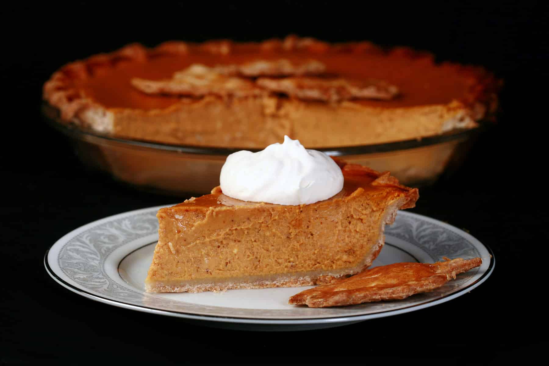 A slice of gluten-free pumpkin pie topped with maple whipped cream.