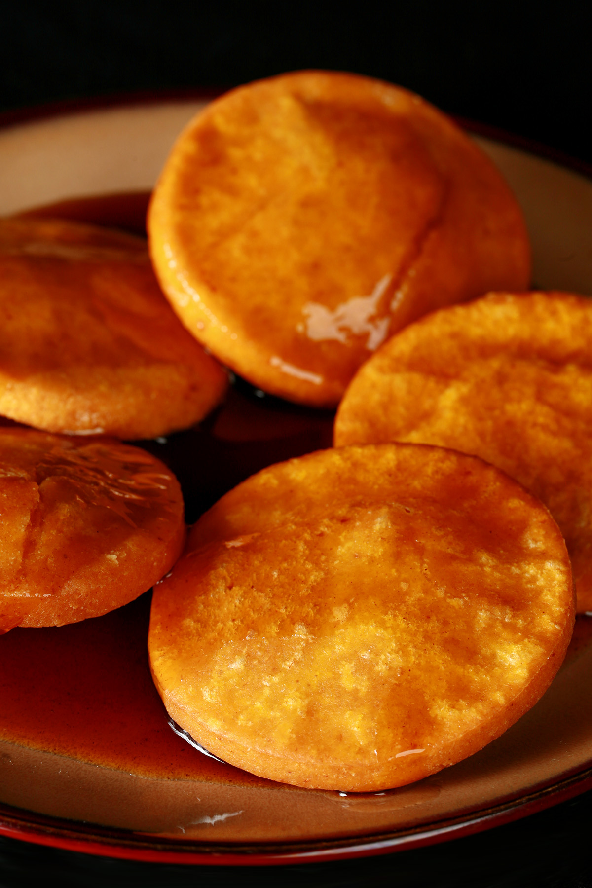 A plate of gluten free sopaipillas pasadas, with sauce drizzled over them.