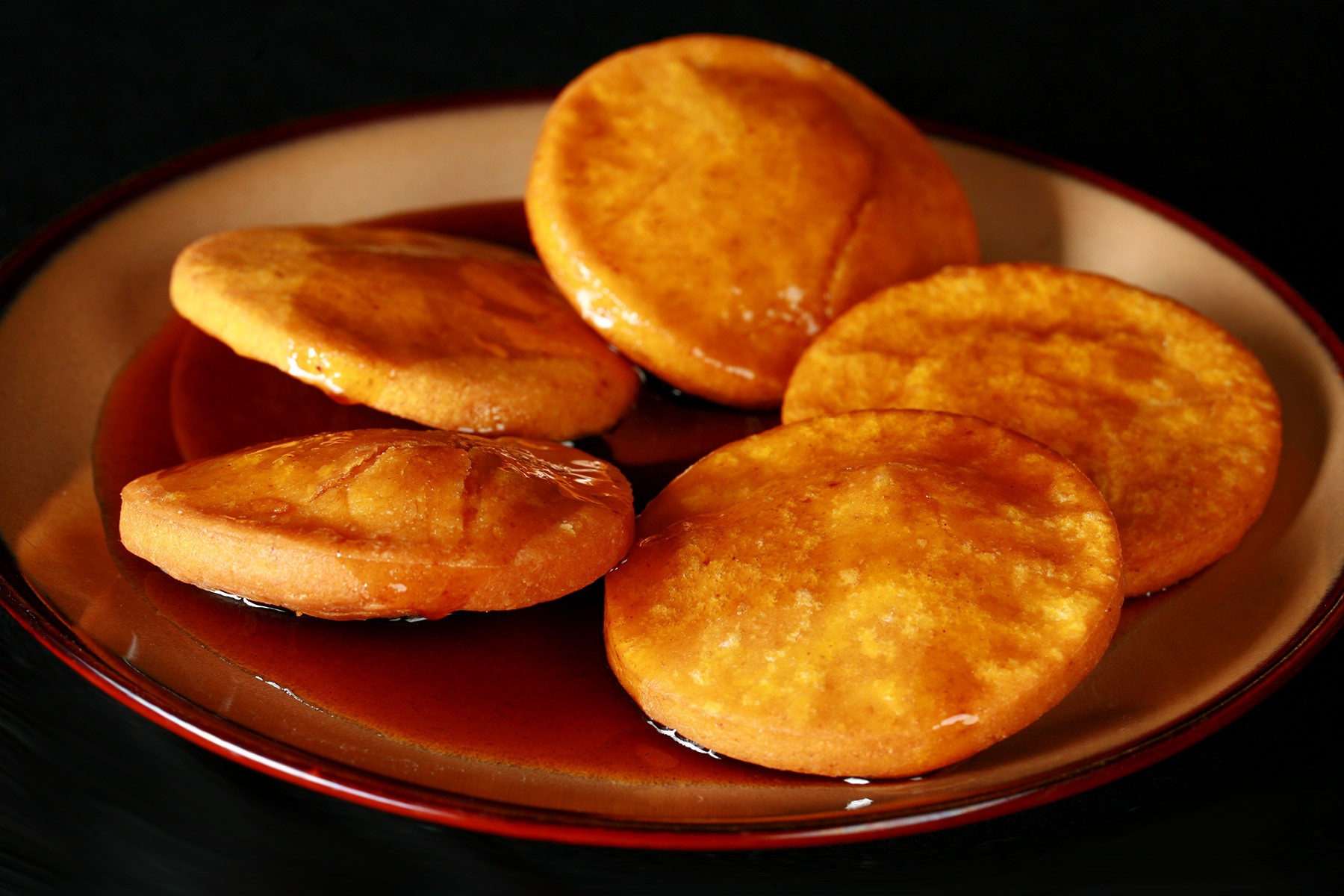 A plate of gluten free sopaipillas pasadas, with sauce drizzled over them.